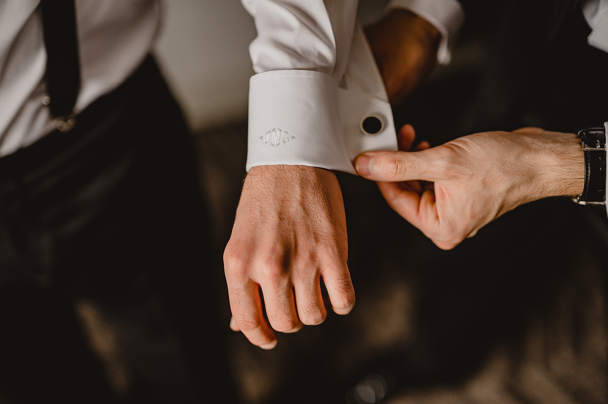 groomsman adjusts cufflinks on wedding day for groom