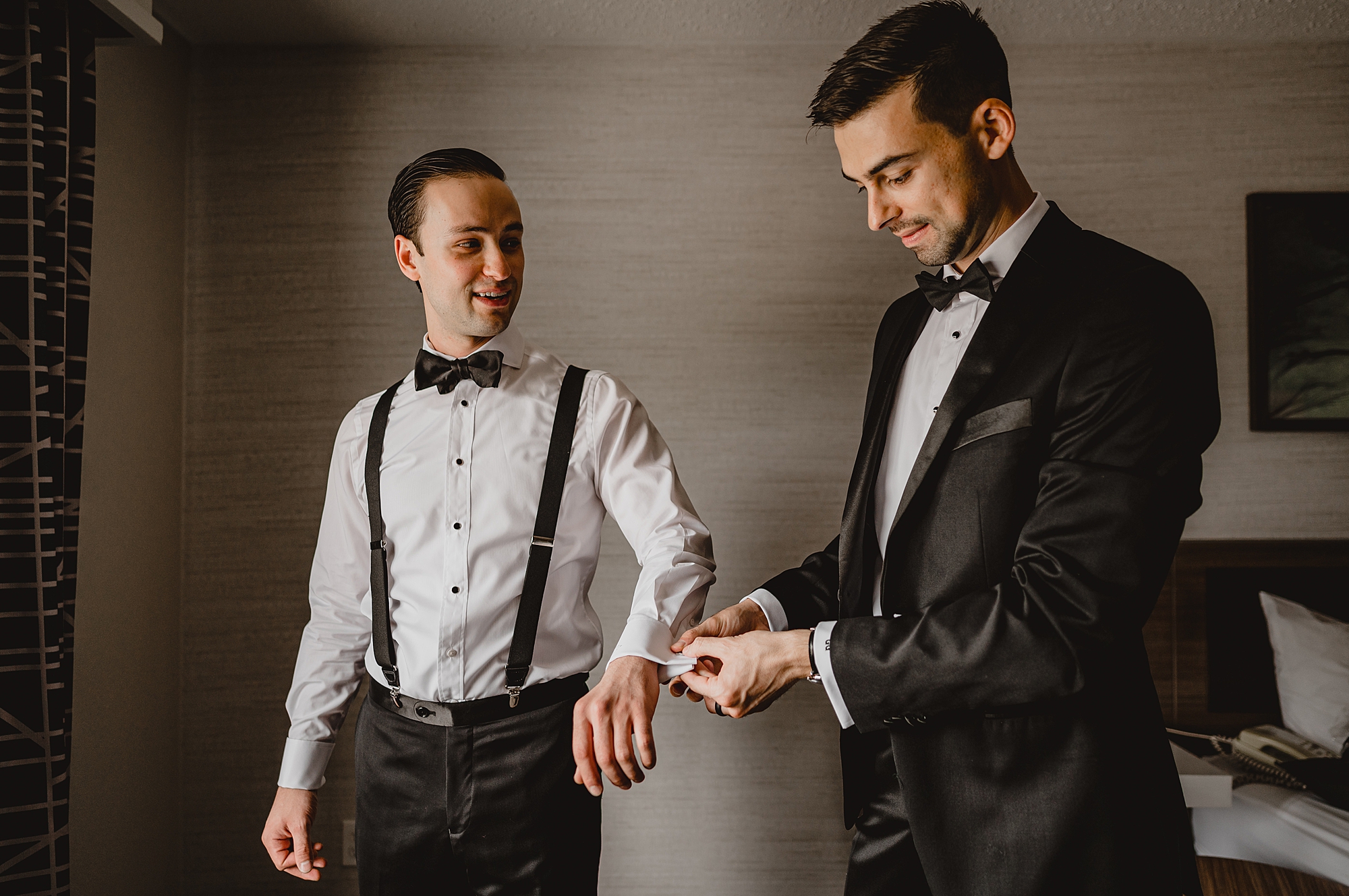 groomsman helps groom adjust cufflinks for wedding day