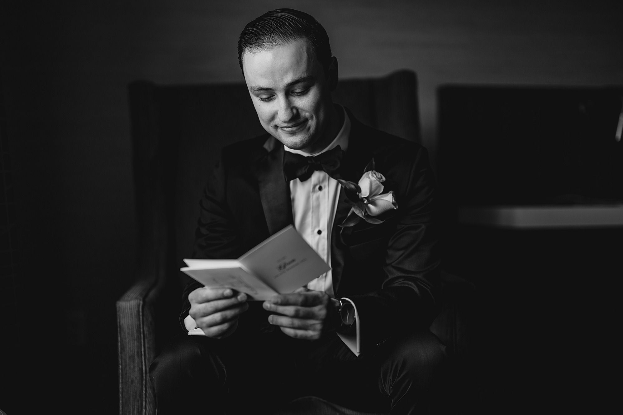 groom reads vow booklet during wedding day 