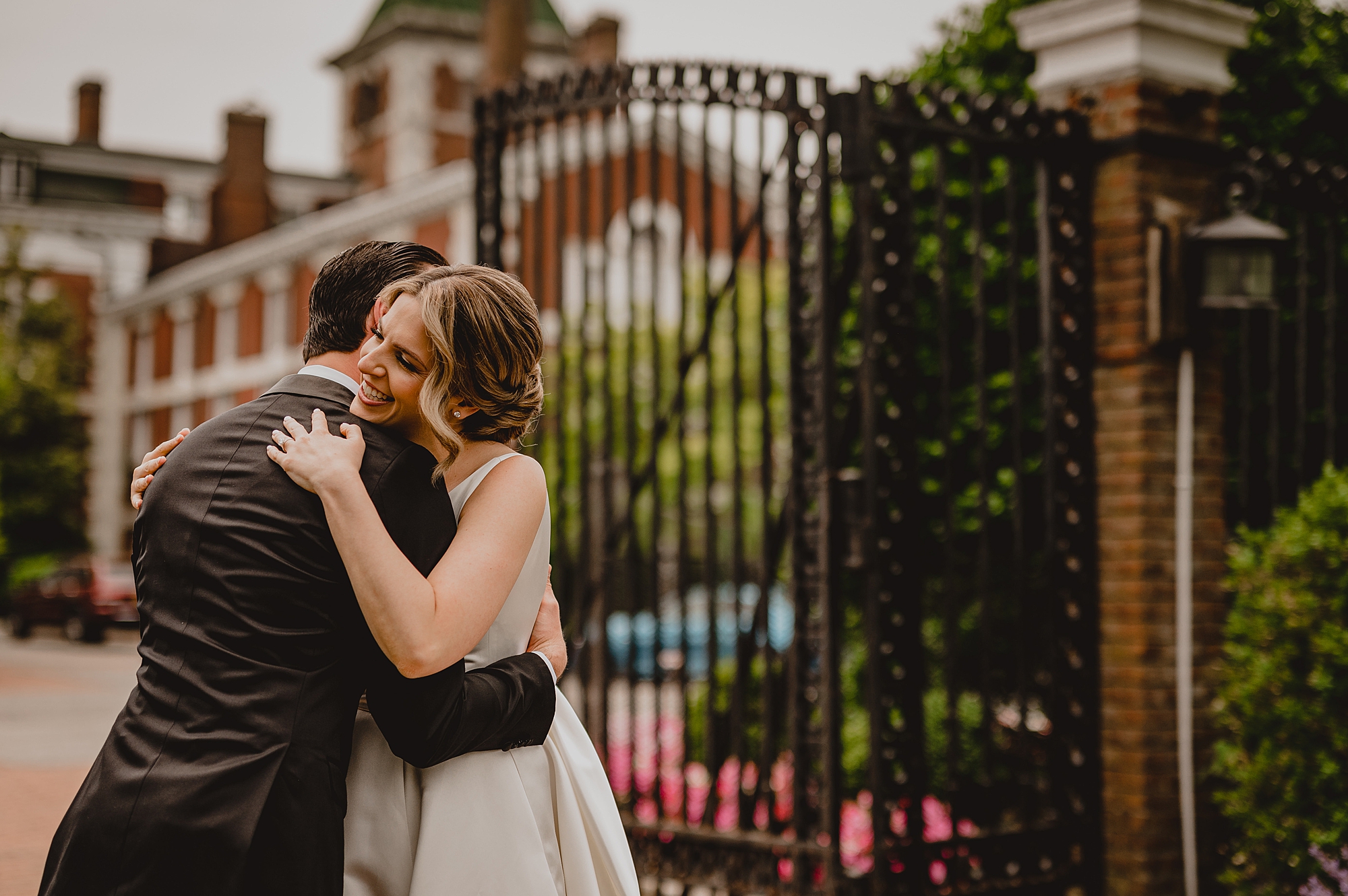 bride and groom kiss in front of iron gates at Bourne Mansion