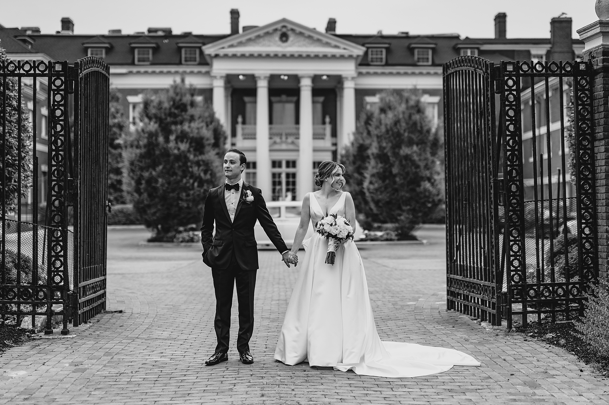 bride and groom hold hands looking away from each other at Bourne Mansion