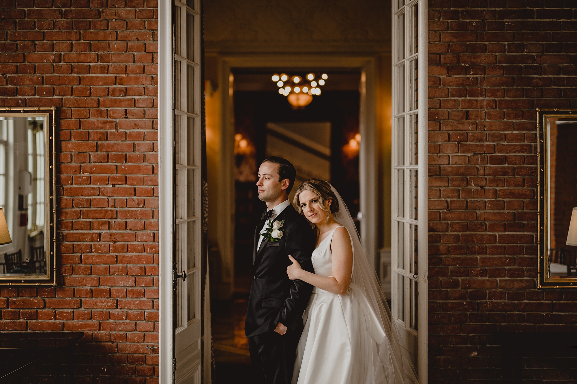bride leans on groom's back outside Bourne Mansion
