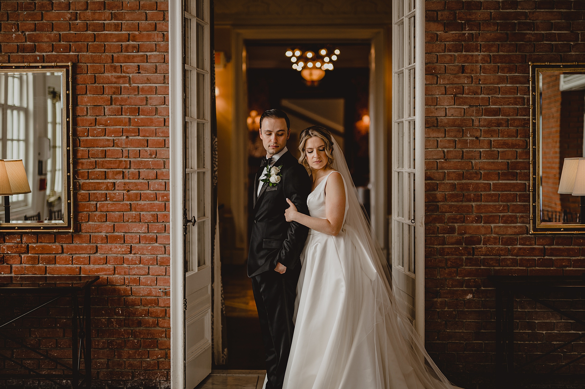 bride leans on groom's back in front of Bourne Mansion