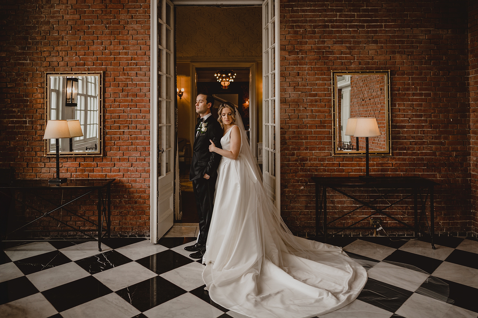 bride and groom hug on black and white floor at Bourne Mansion