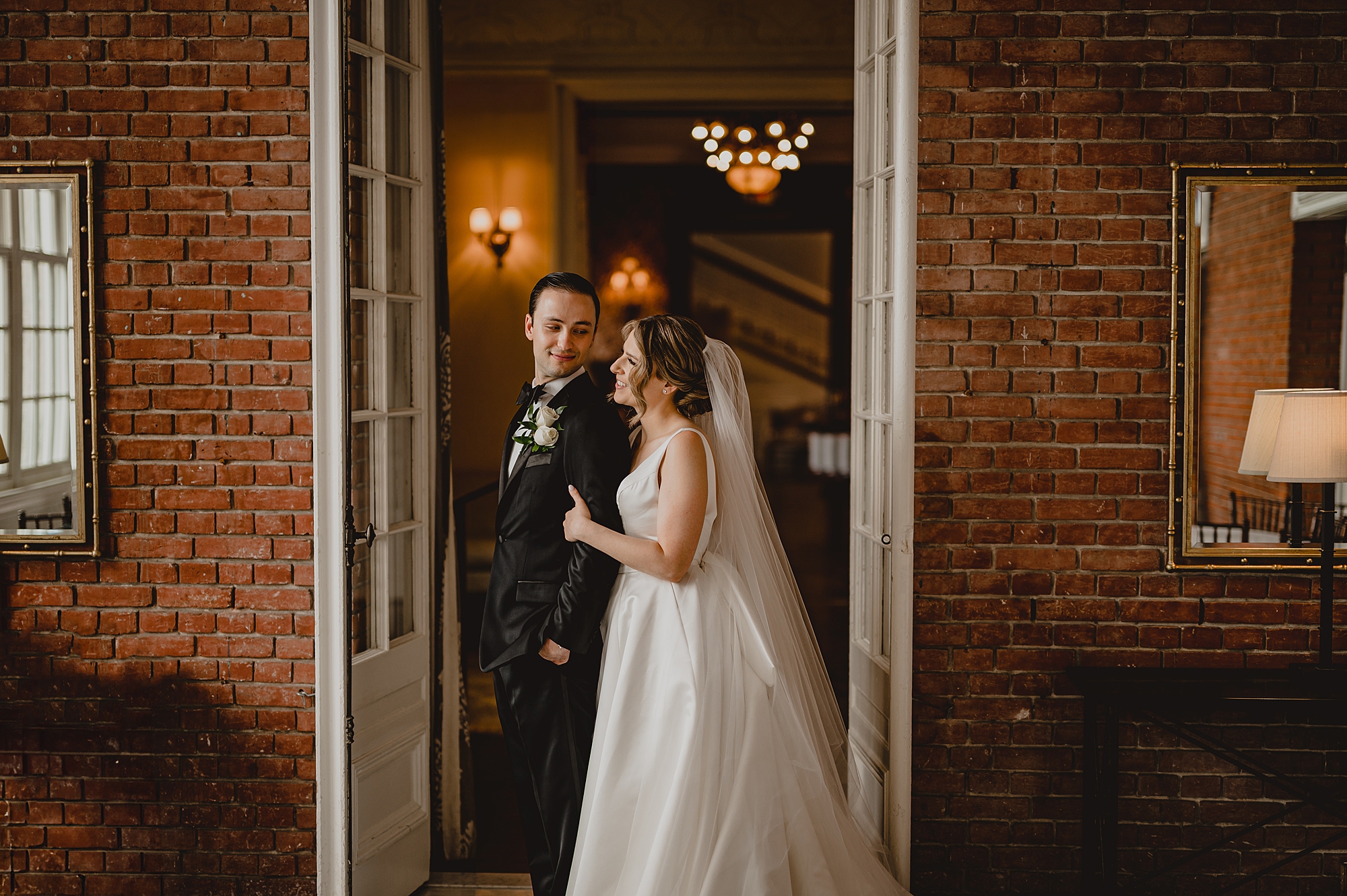 bride and groom hug in front of Bourne Mansion
