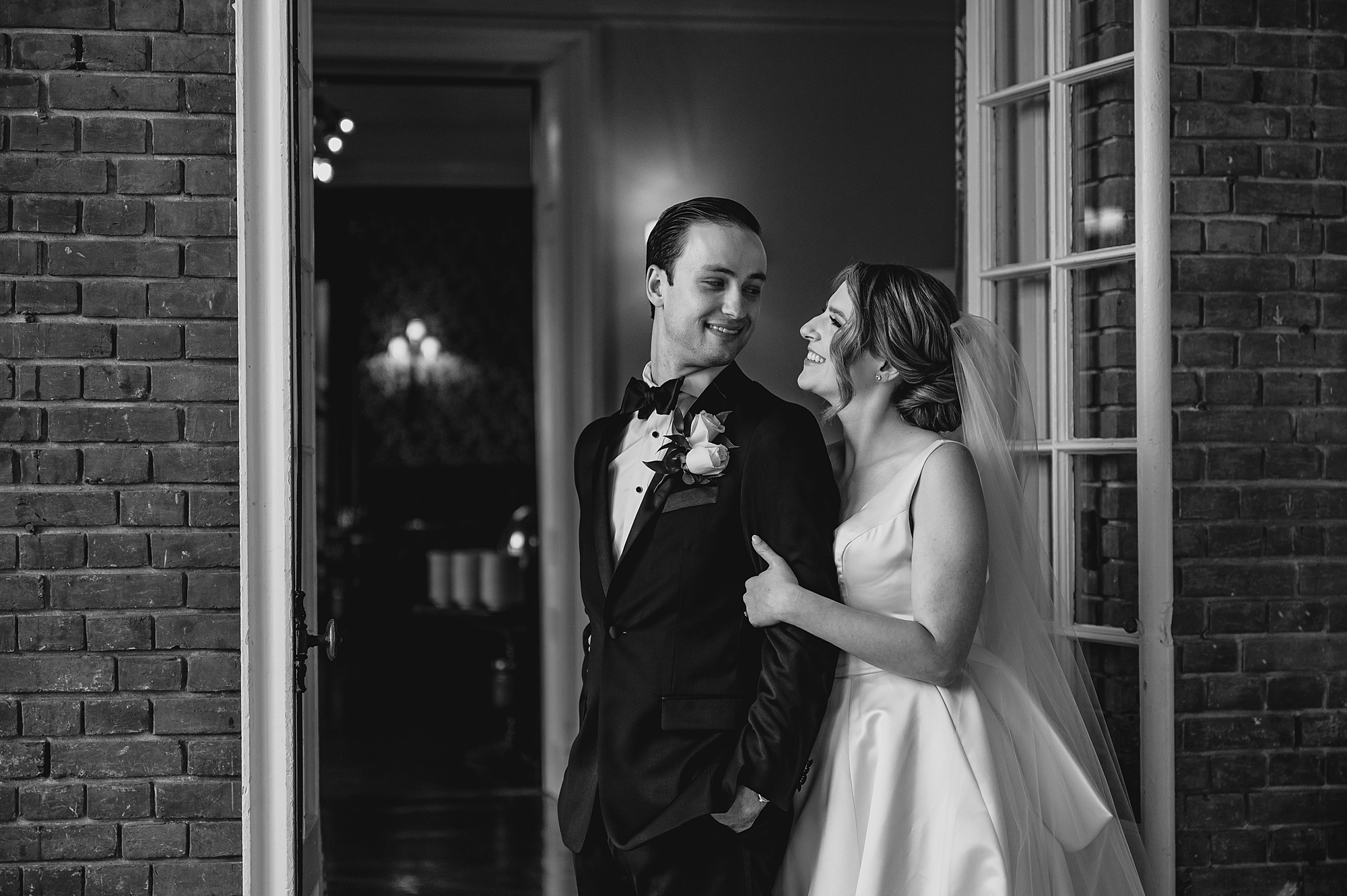 bride looks at groom while holding his arm in front of library at Bourne Mansion