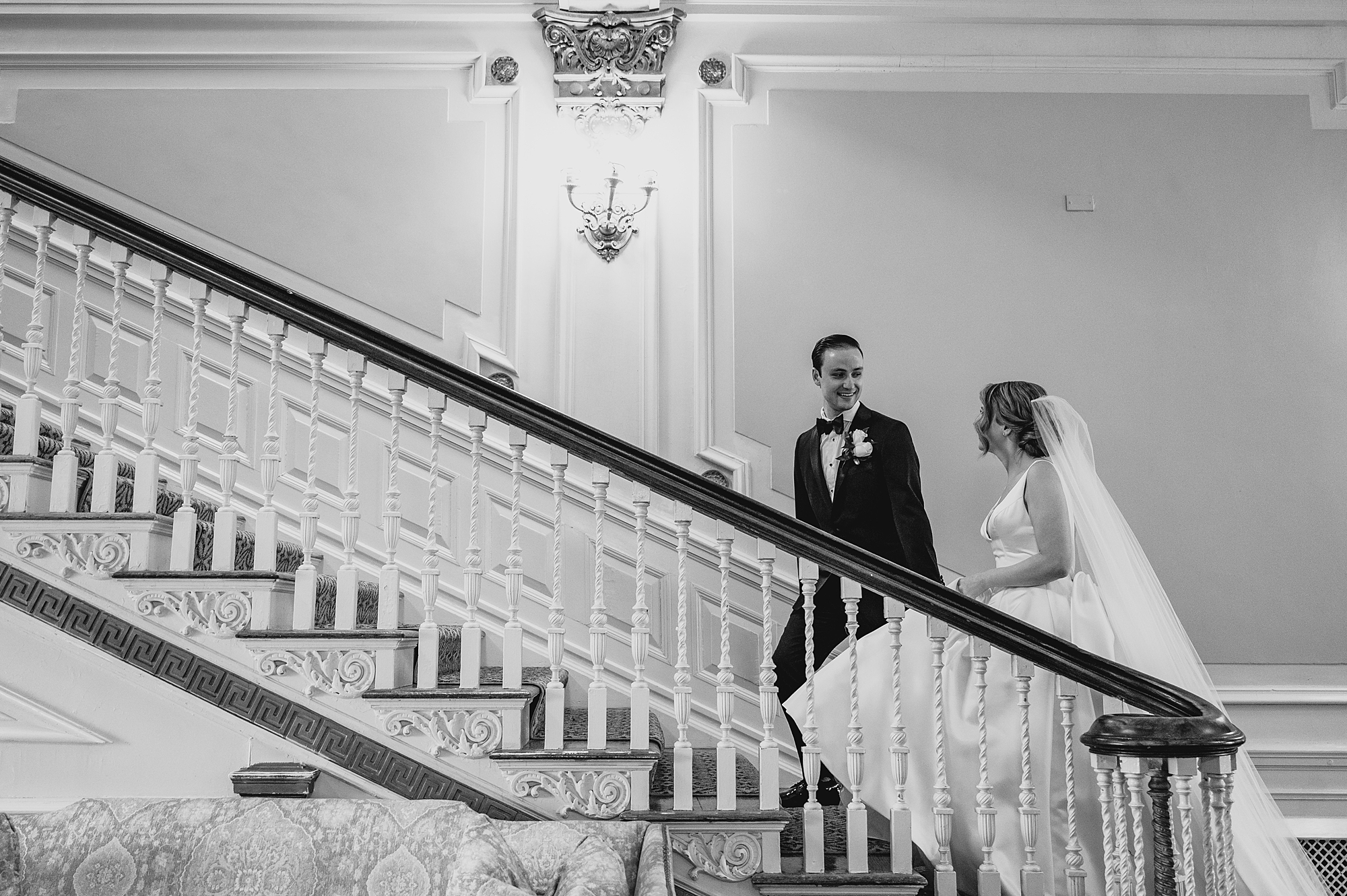 bride and groom walk up staircase inside Bourne Mansion