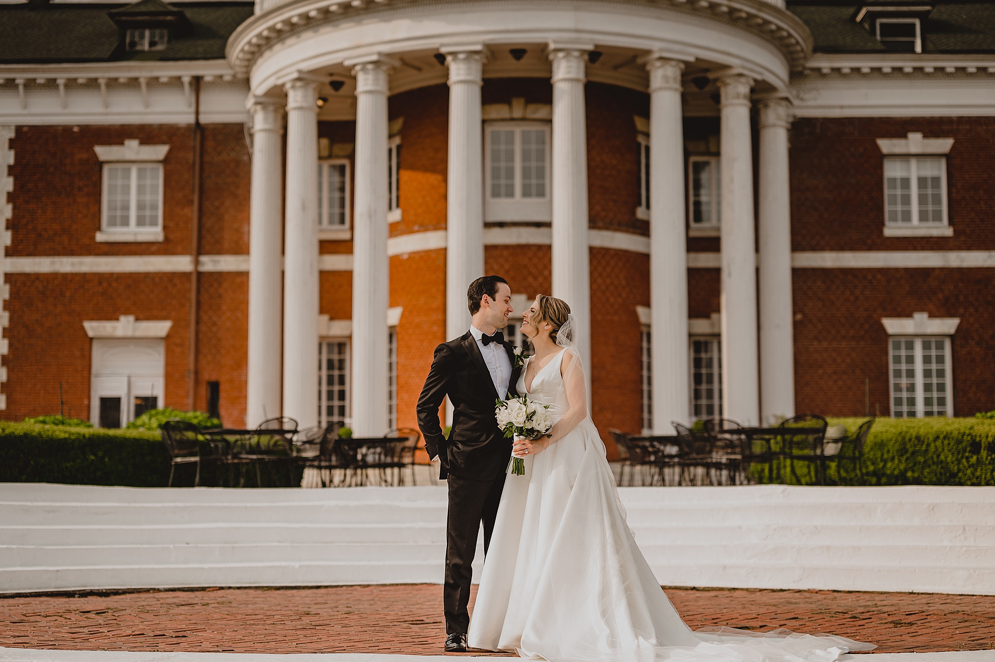 newlyweds kiss in front of rotunda at Bourne Mansion
