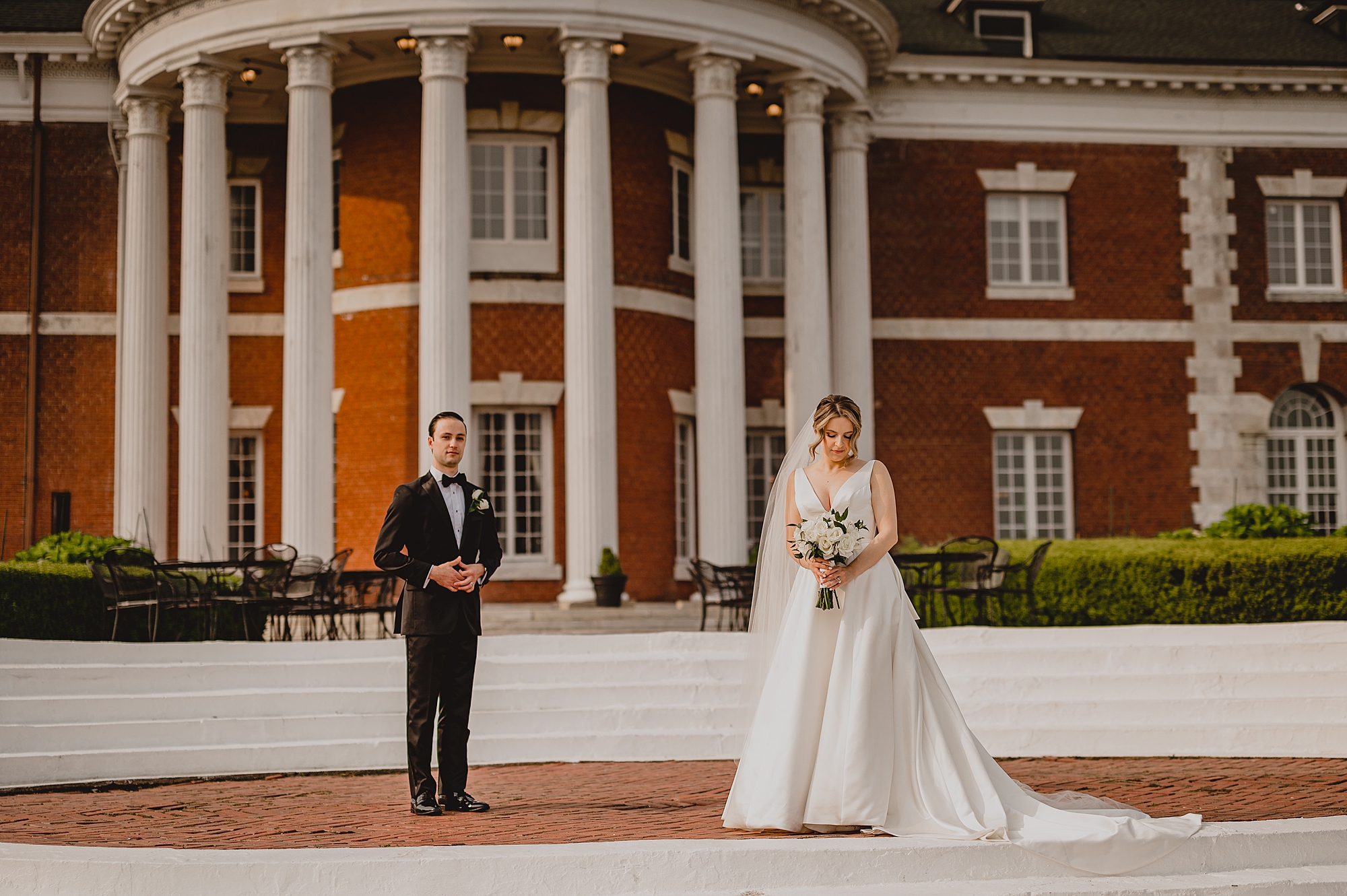 groom and bride stand far apart outside Bourne Mansion