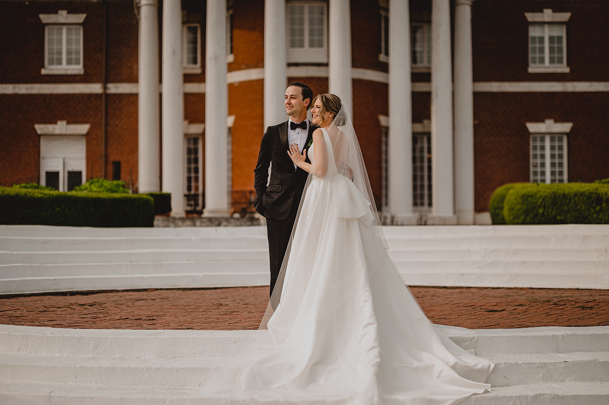 bride leans into groom's chest outside Bourne Mansion
