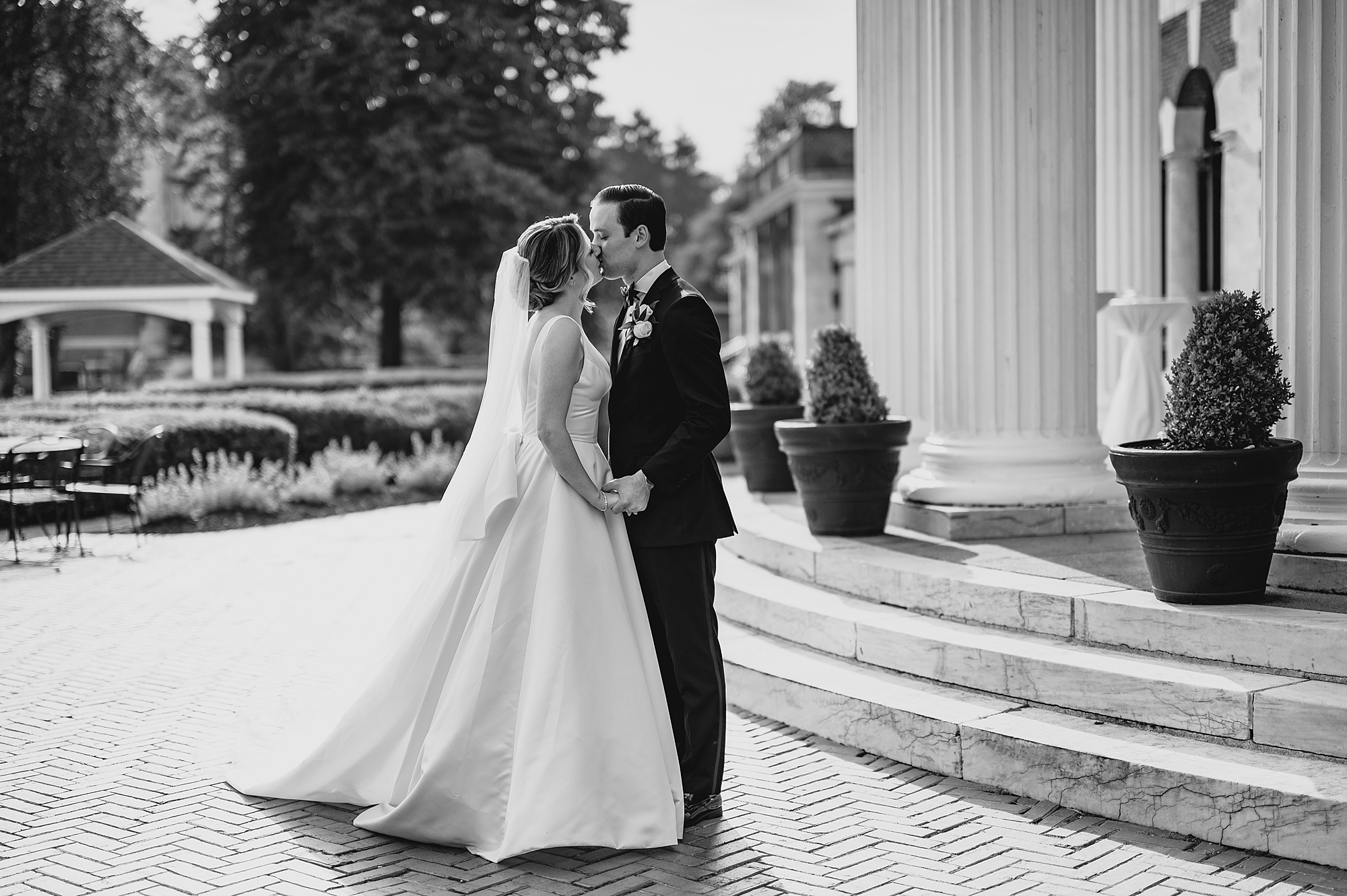 bride and groom kiss outside the rotunda at Bourne Mansion