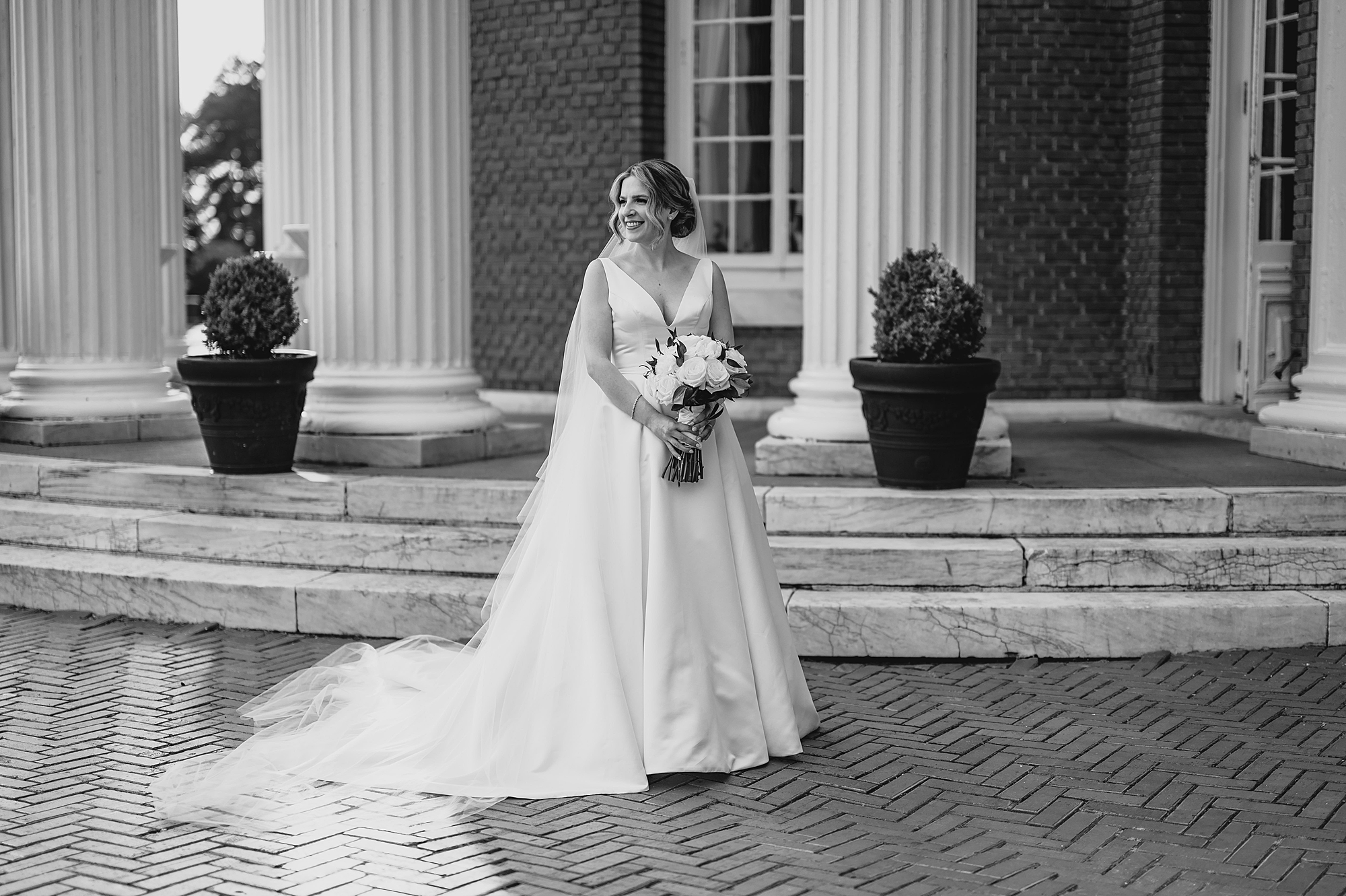 bride stands outside rotunda at Bourne Mansion