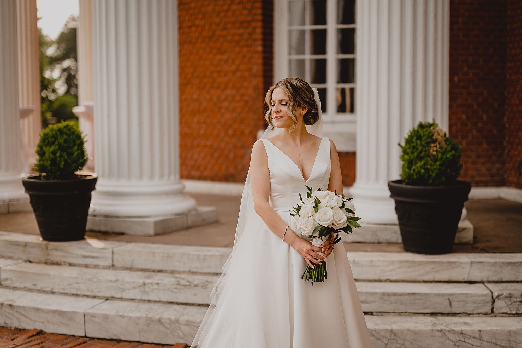bride holds bouquet of white flowers outside Bourne Mansion