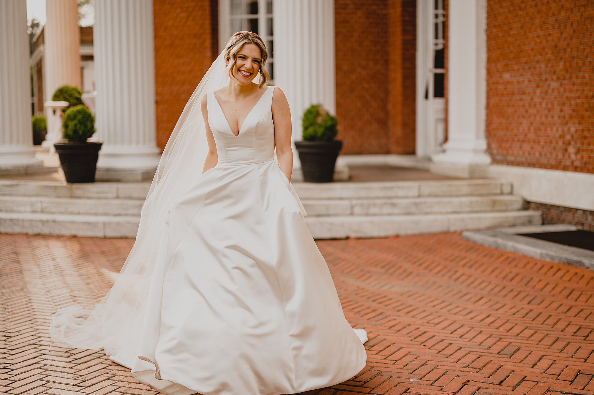 bride holds skirt of wedding dress walking on patio