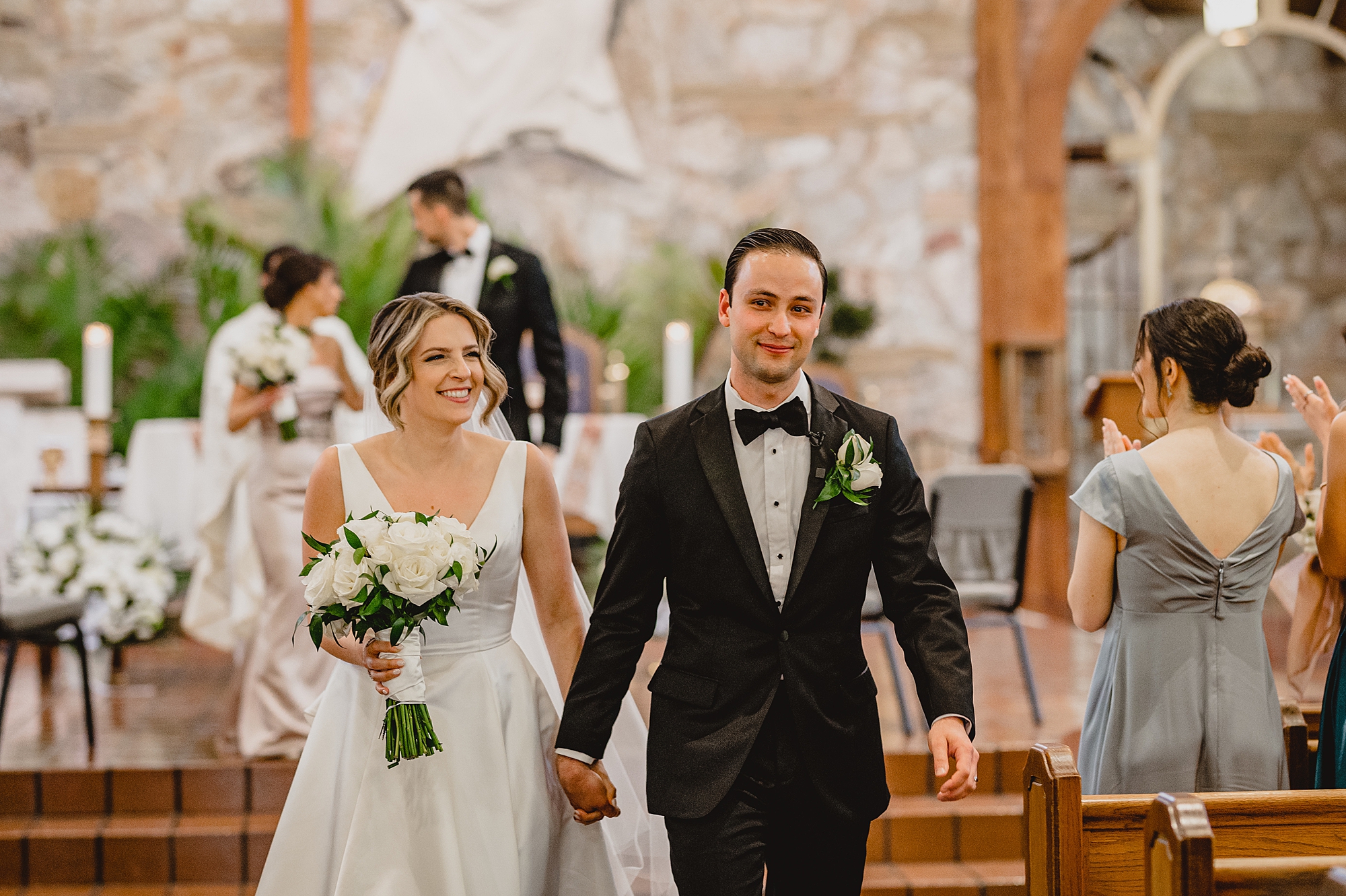 bride and groom hold hands walking up aisle after traditional church wedding on Long Island NY