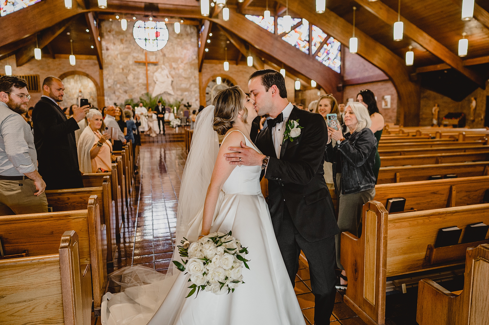 bride and groom kiss in aisle after traditional church wedding on Long Island NY