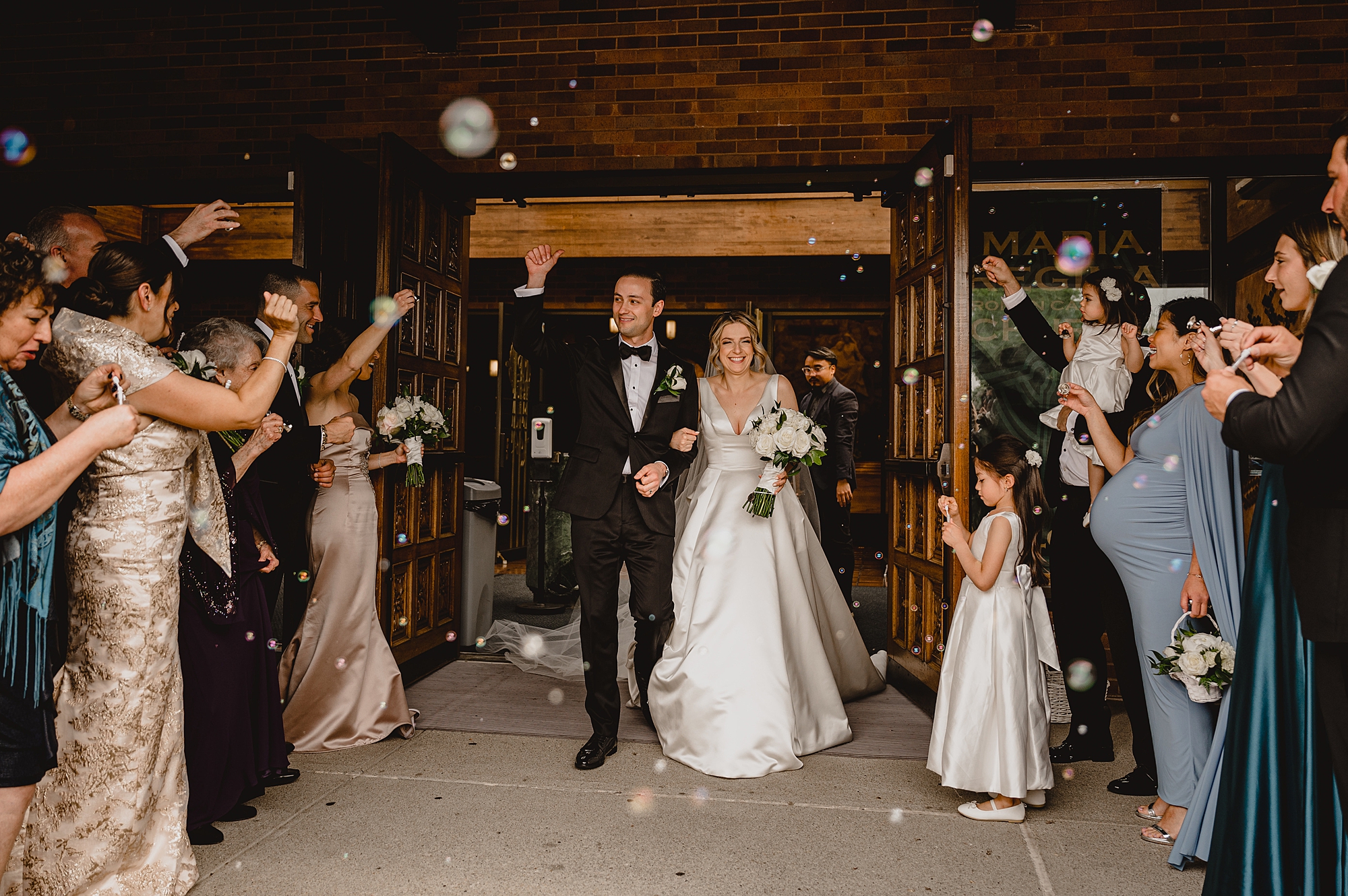 newlyweds leave wedding ceremony with guests blowing bubbles 