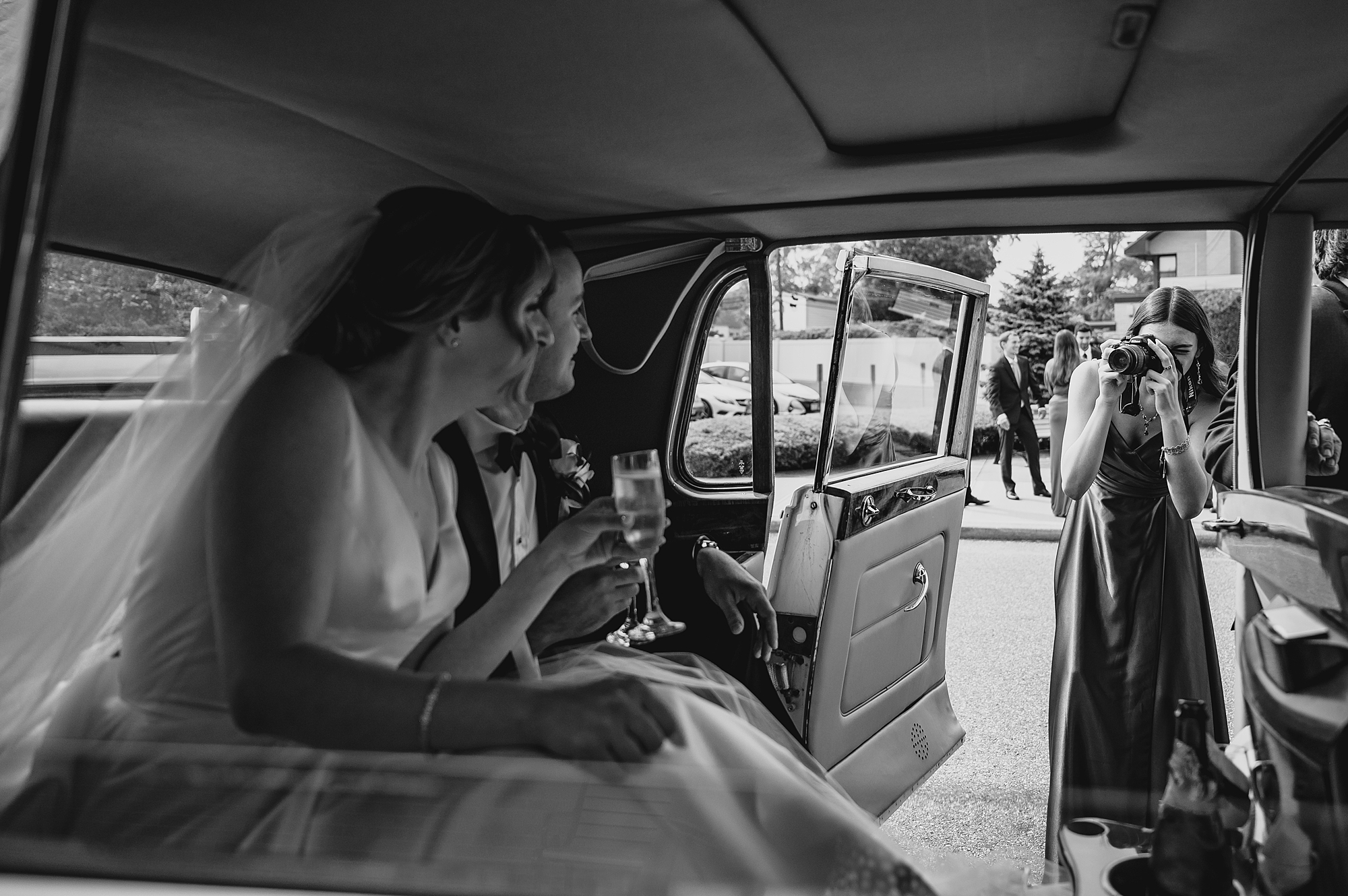 bride and groom sit in back of classic car 