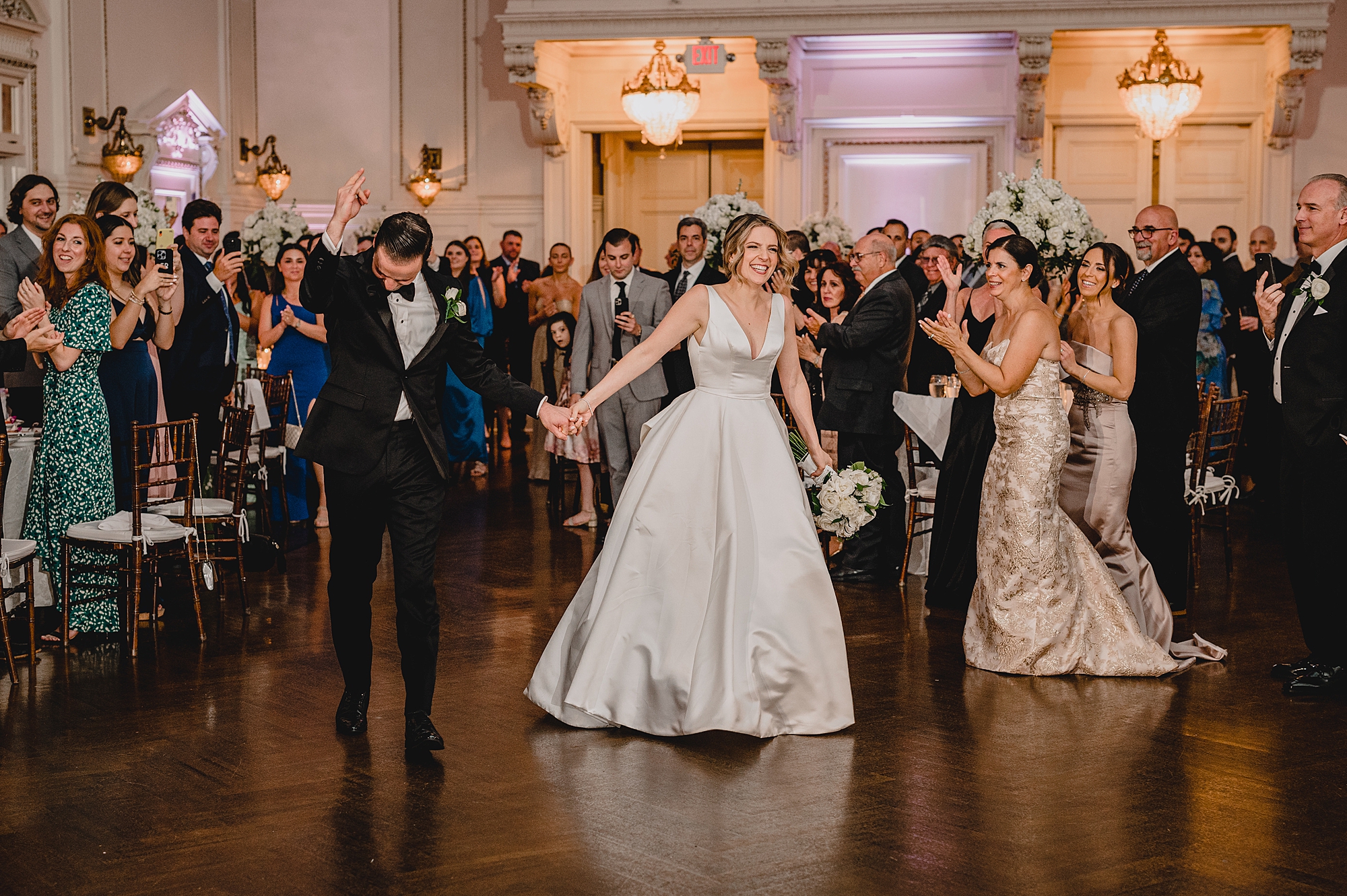 newlyweds hold hands walking into reception at Bourne Mansion