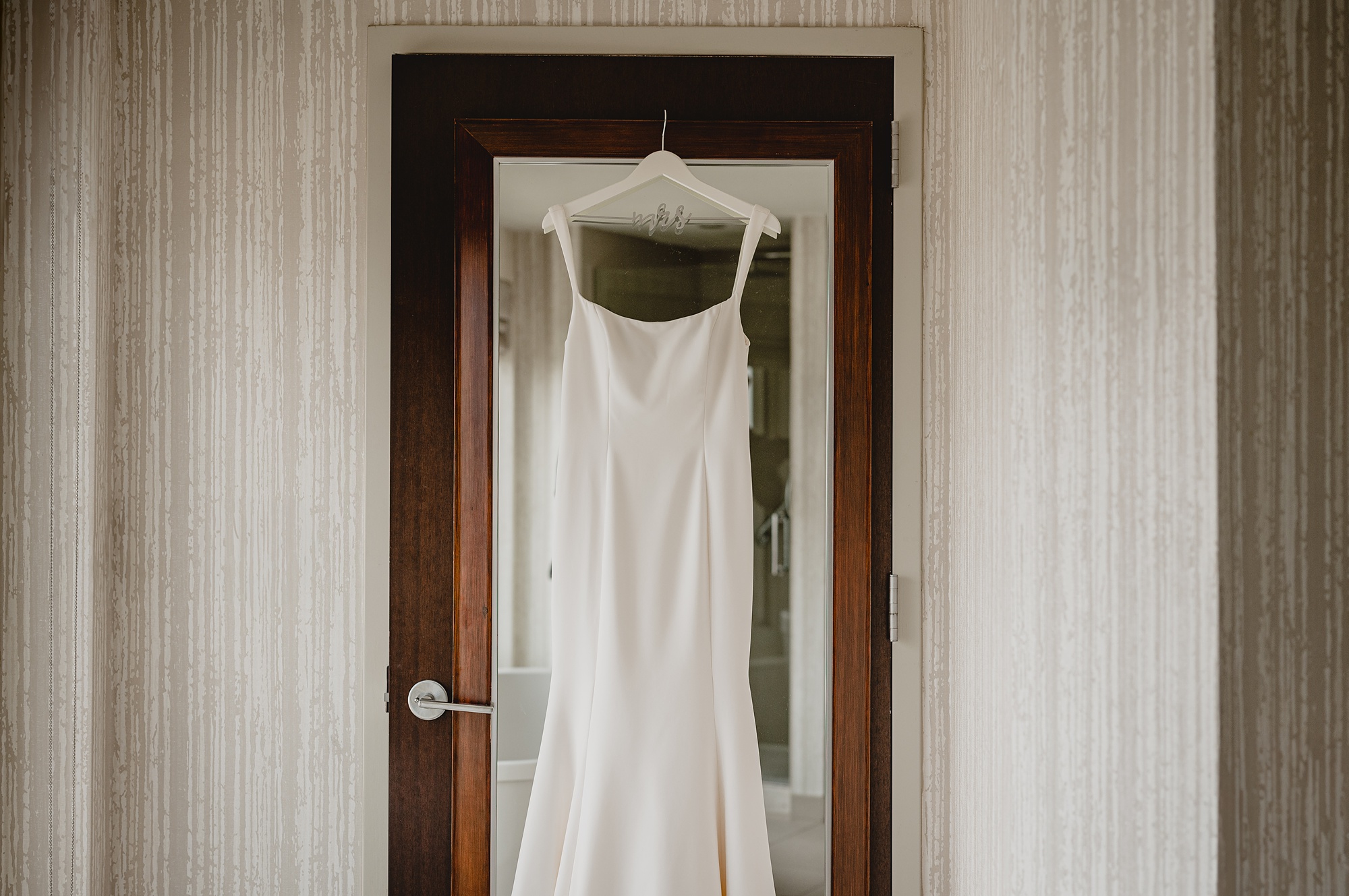 wedding dress hangs on mirror of suite in New Jersey hotel