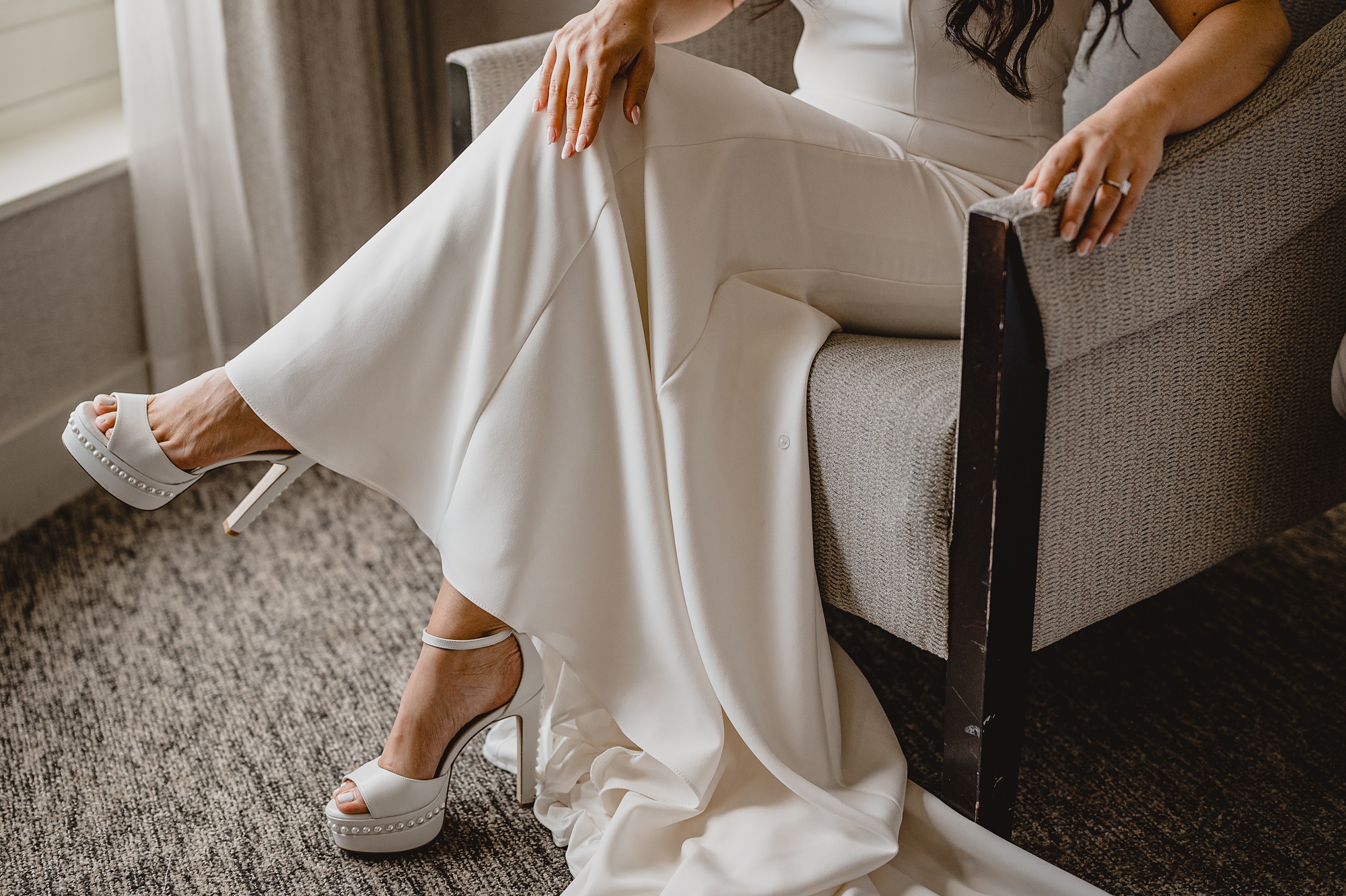 bride sits in white chair of hotel room