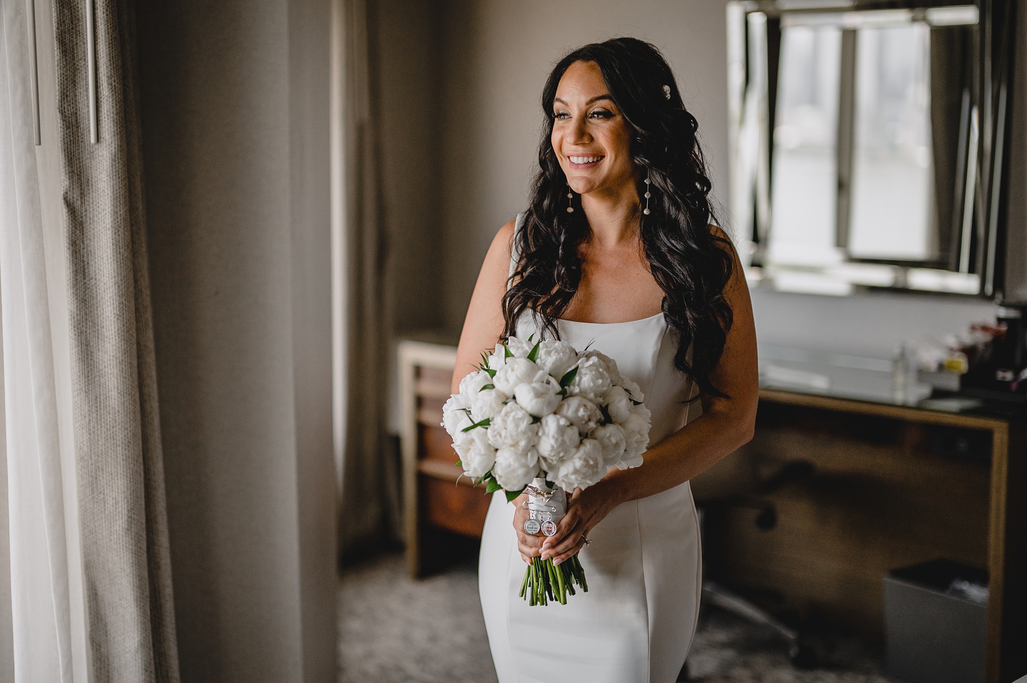 bride smiles wearing strapless gown with white flowers in front of her