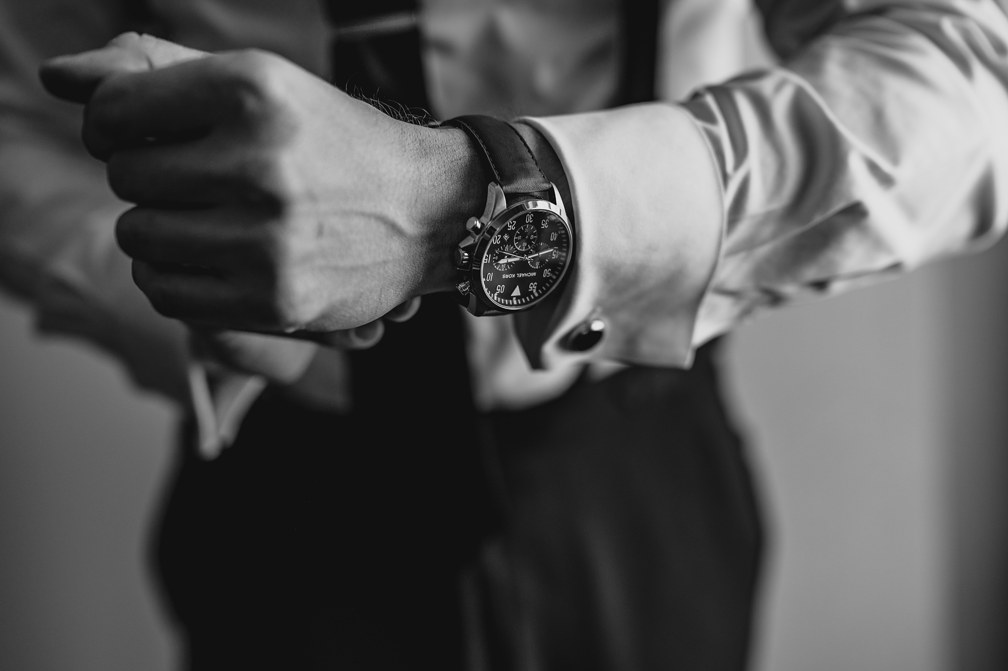 groom adjust cufflinks showing off watch during wedding at Liberty House