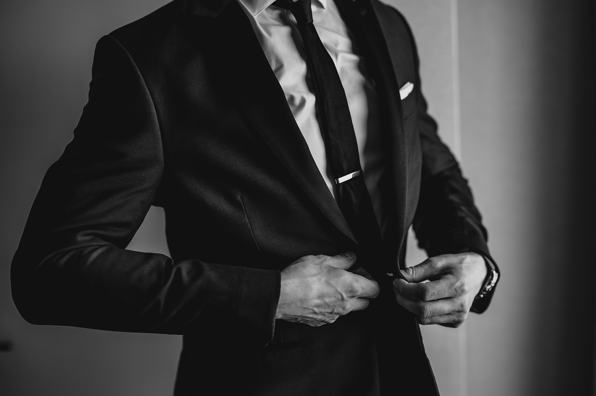 groom buttons up suit jacket during prep at New Jersey hotel