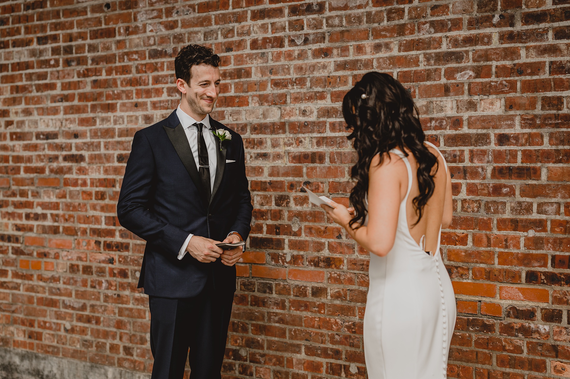 groom looks at private vows during first look at the Liberty House