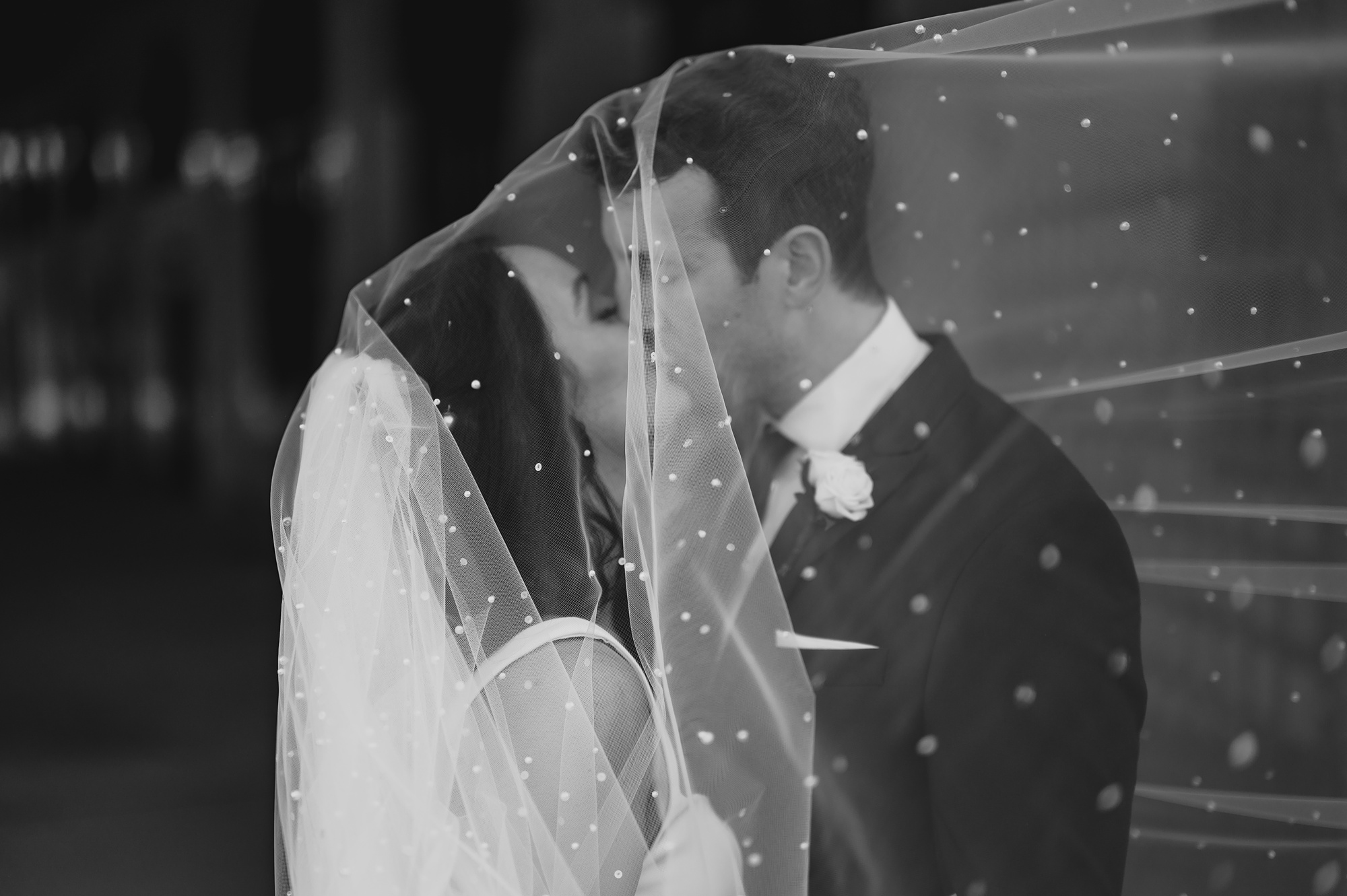 newlyweds kiss under veil with sparkly accents at the Liberty House