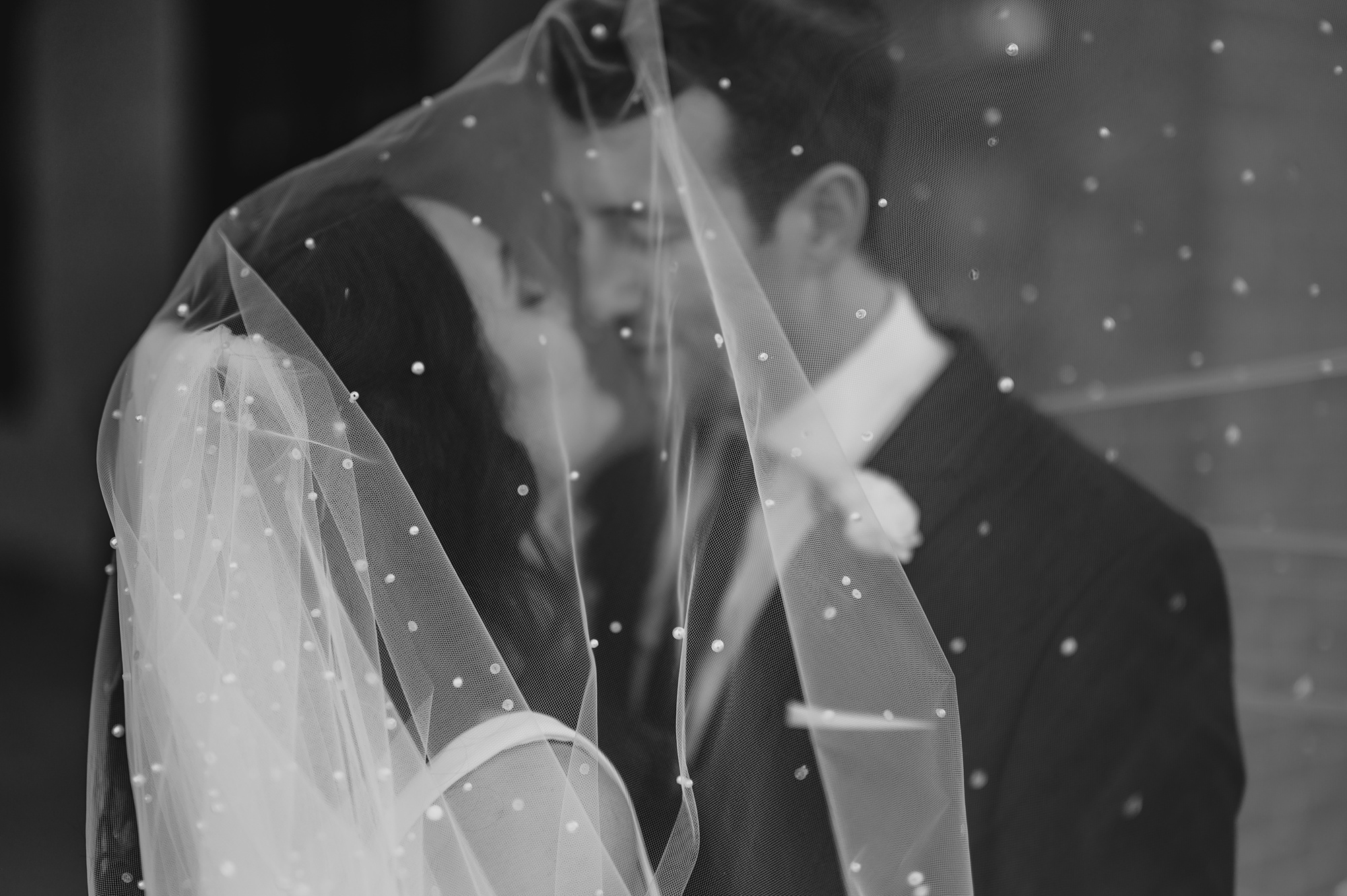 bride and groom kiss under veil with sparkles