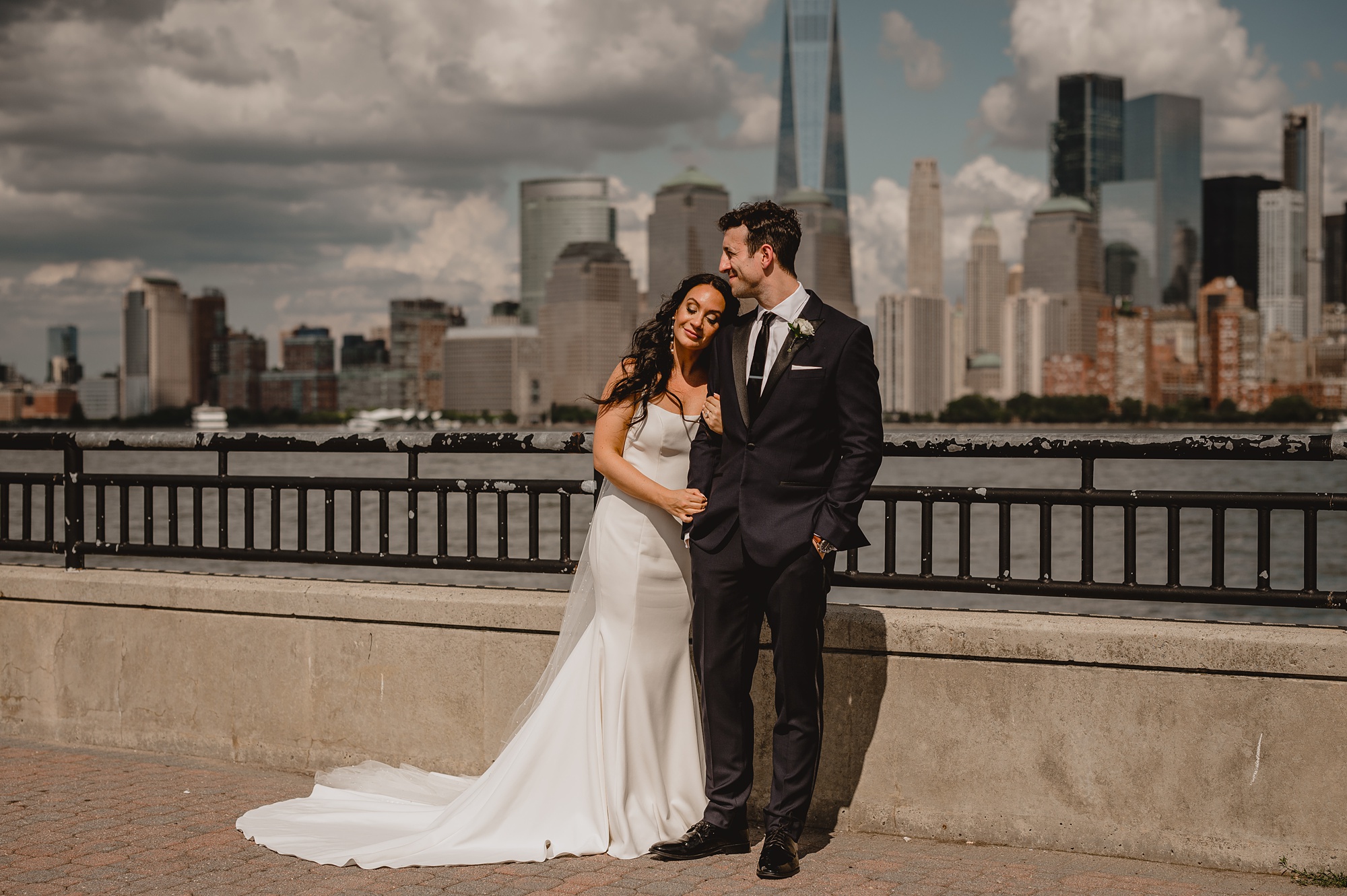 newlyweds hug in front of the Hudson River at the Liberty House