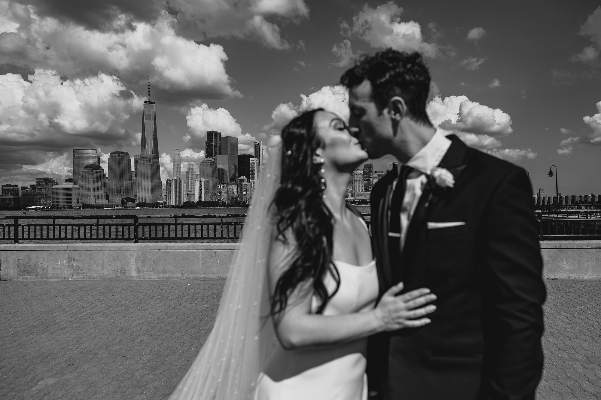 newlyweds kiss with NYC skyline behind them in front of the Hudson River