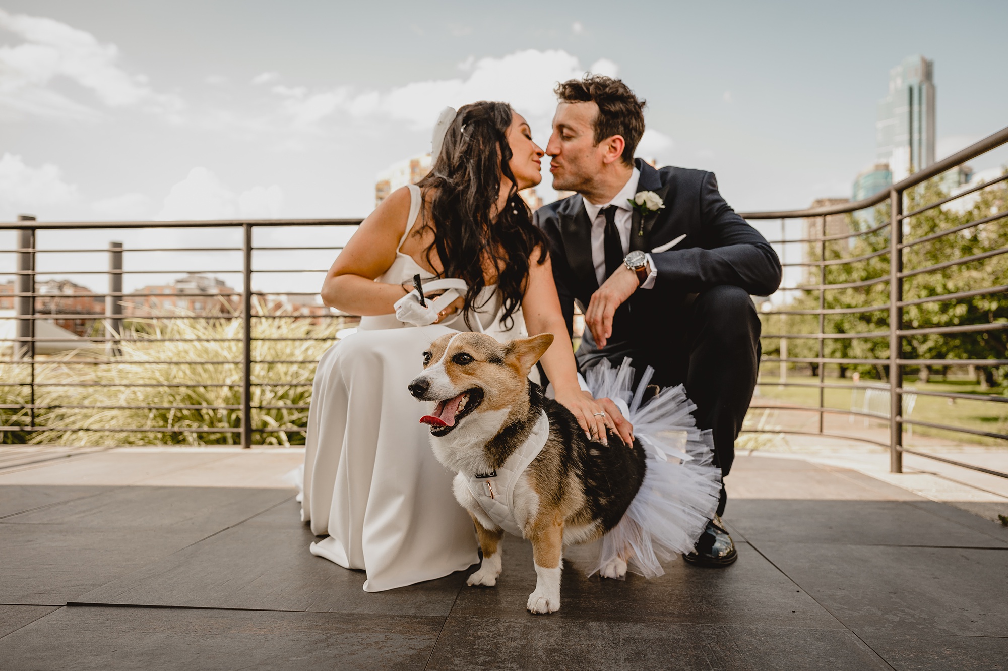 newlyweds kneel kissing with dog in tutu during wedding day at the Liberty House