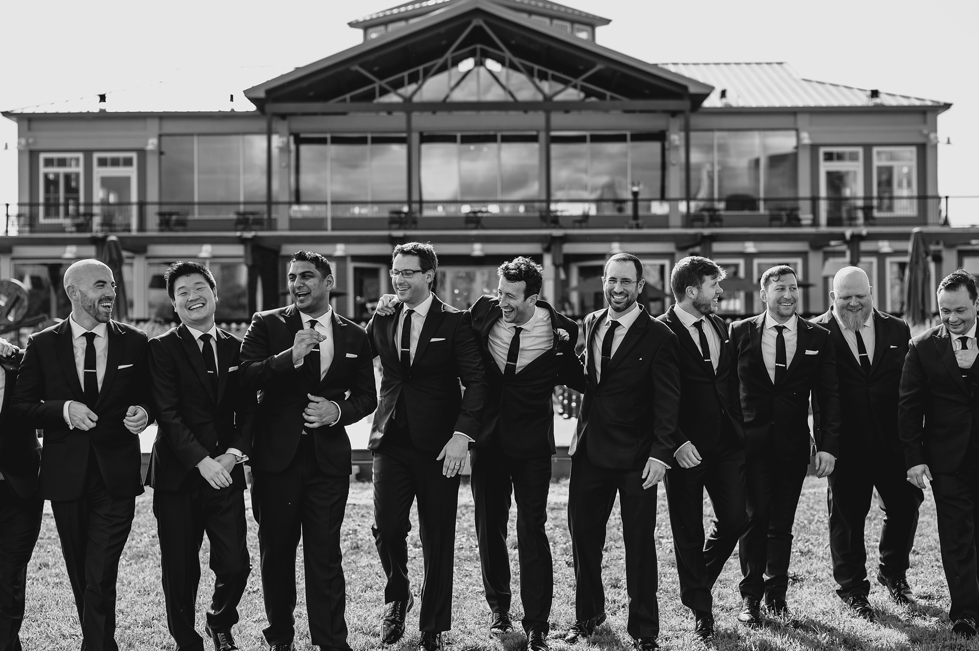 groom walks with groomsmen on lawn at the Liberty House