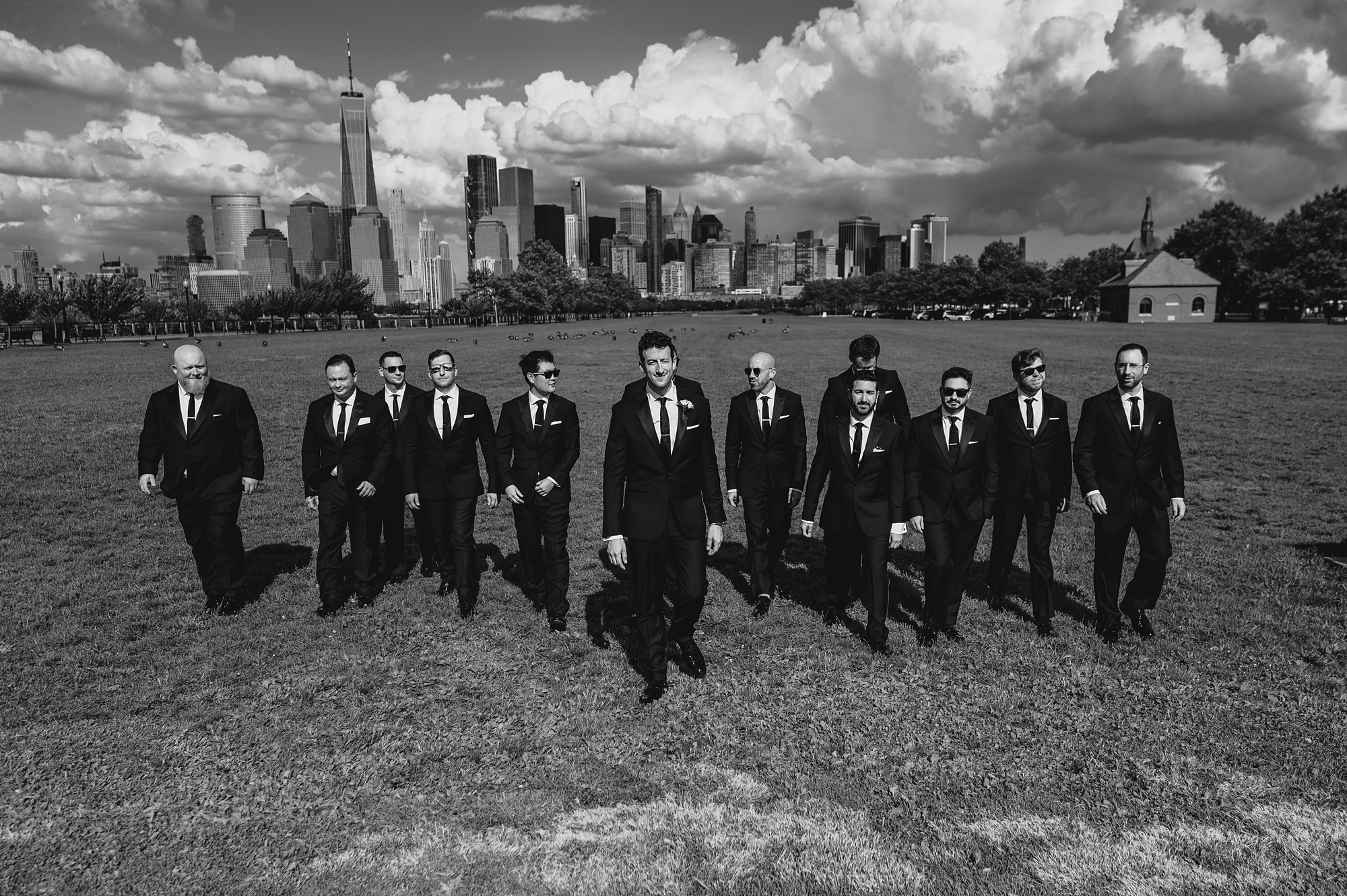 groom walks with groomsmen in front of NYC skyline