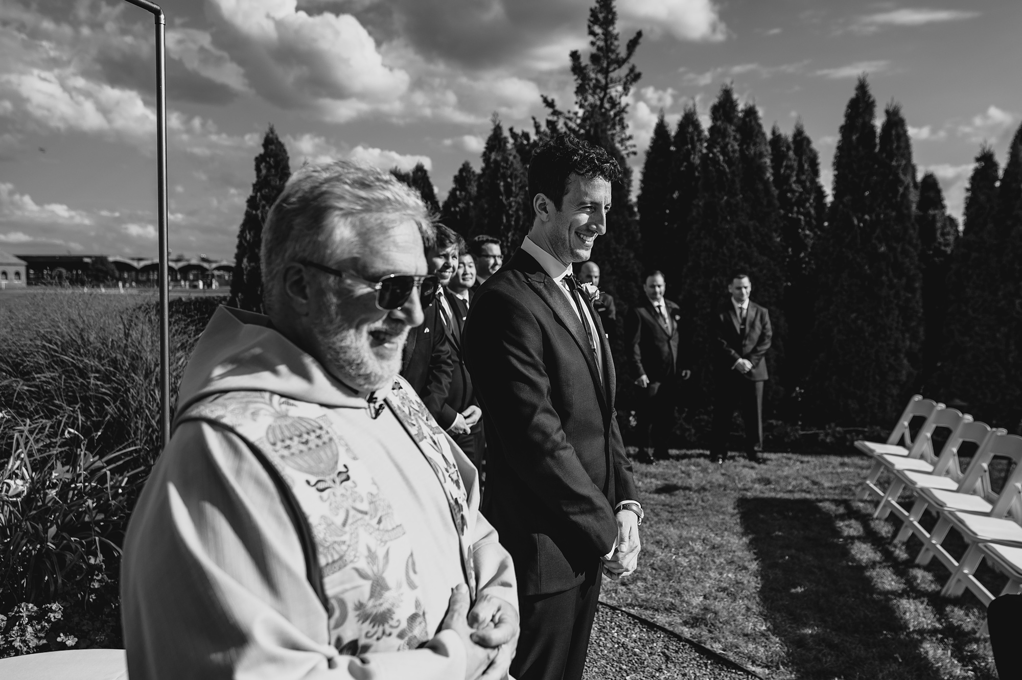 groom walks with priest to ceremony on patio at the Liberty House