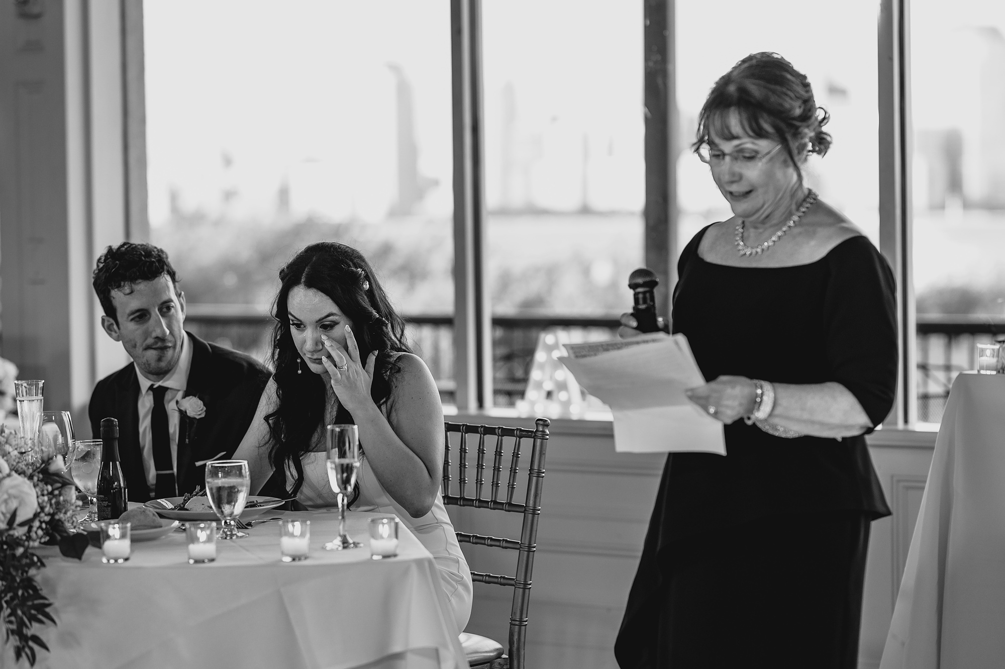 mother reads speech next to sweetheart table at wedding reception