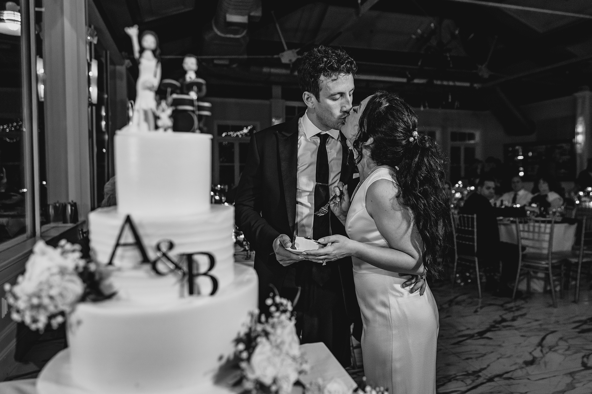 bride and groom kiss by tiered wedding cake at the Liberty House