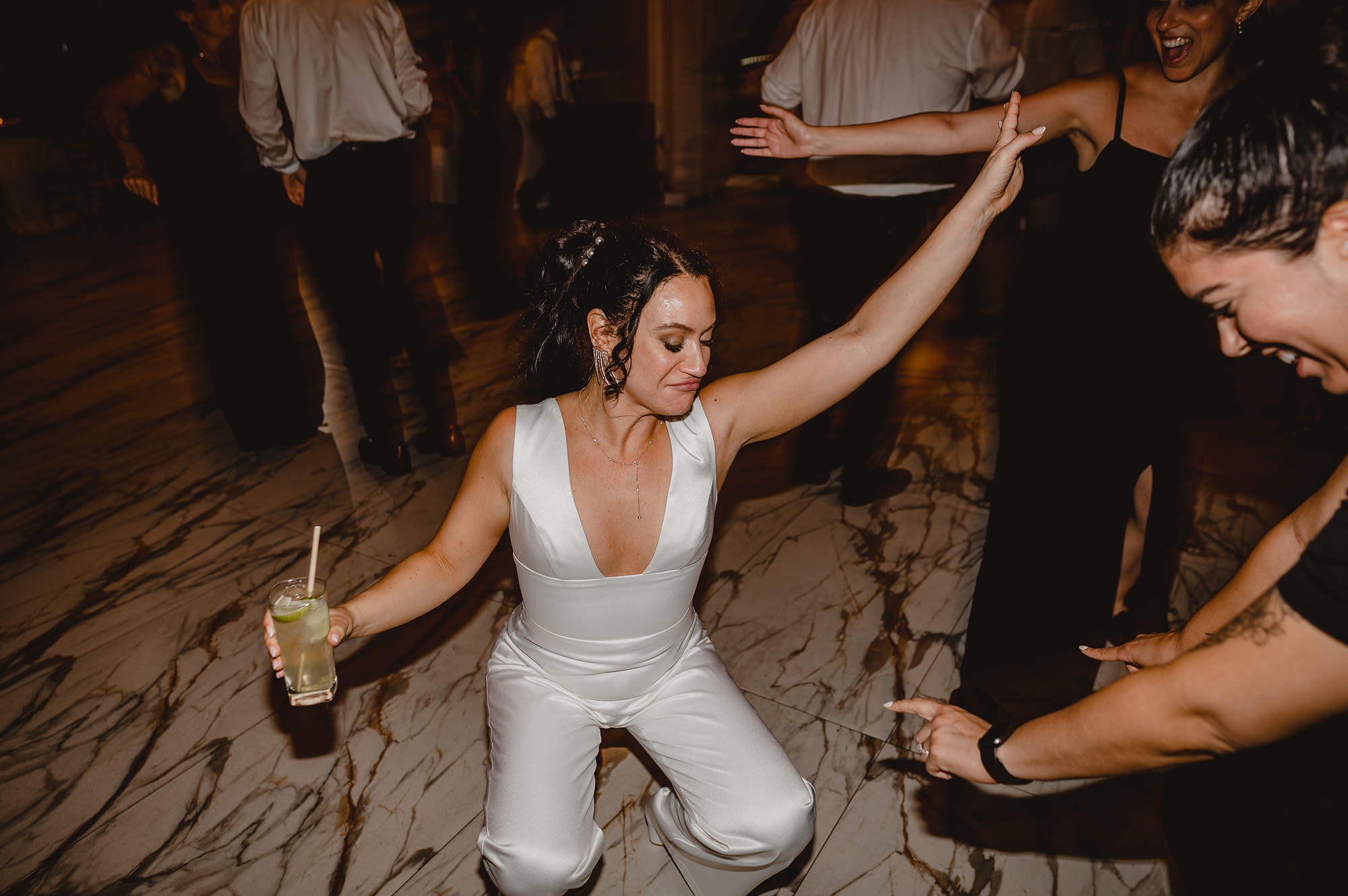 bride dances during reception in white jumpsuit