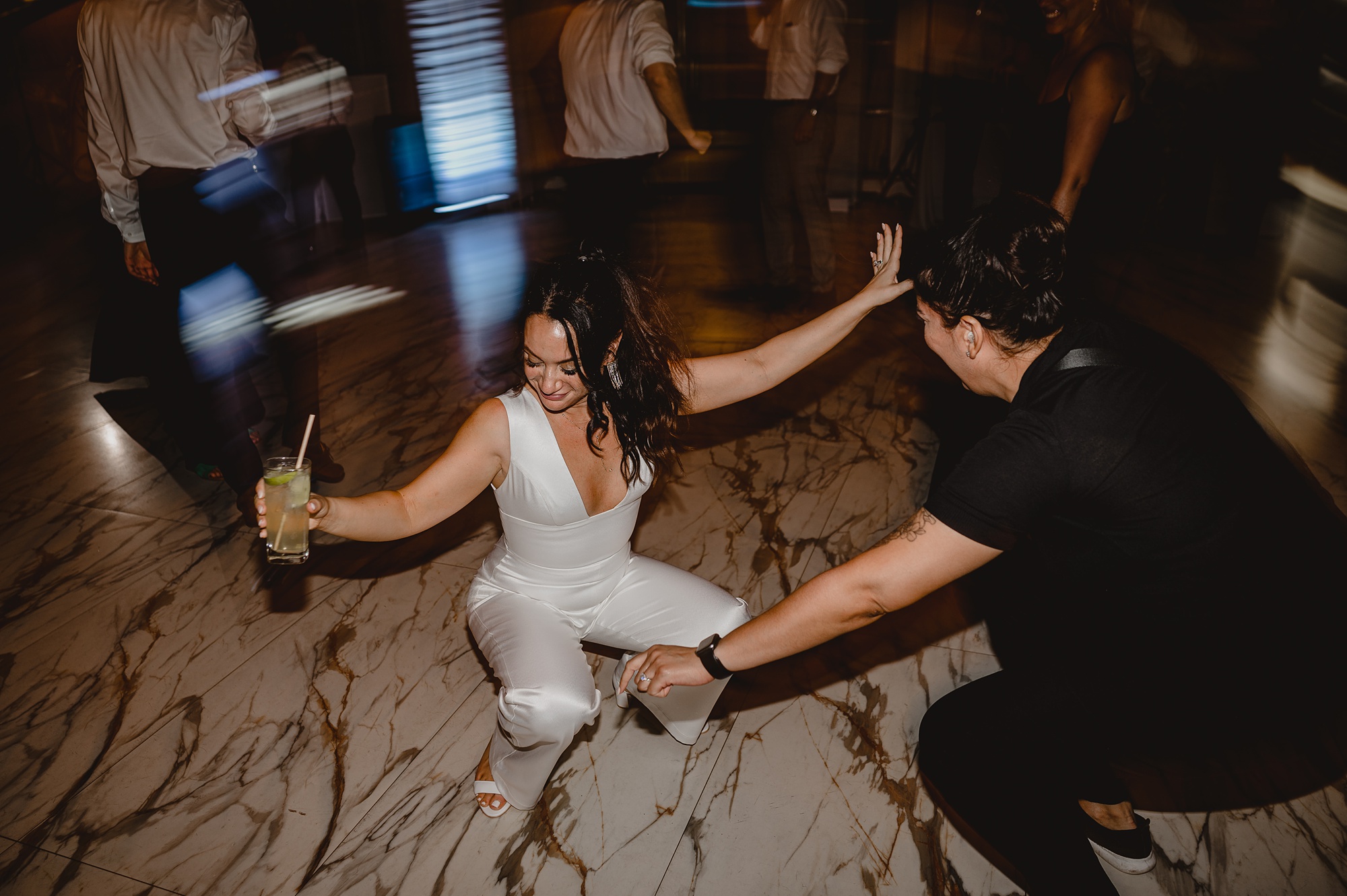bride dances during reception in white jumpsuit