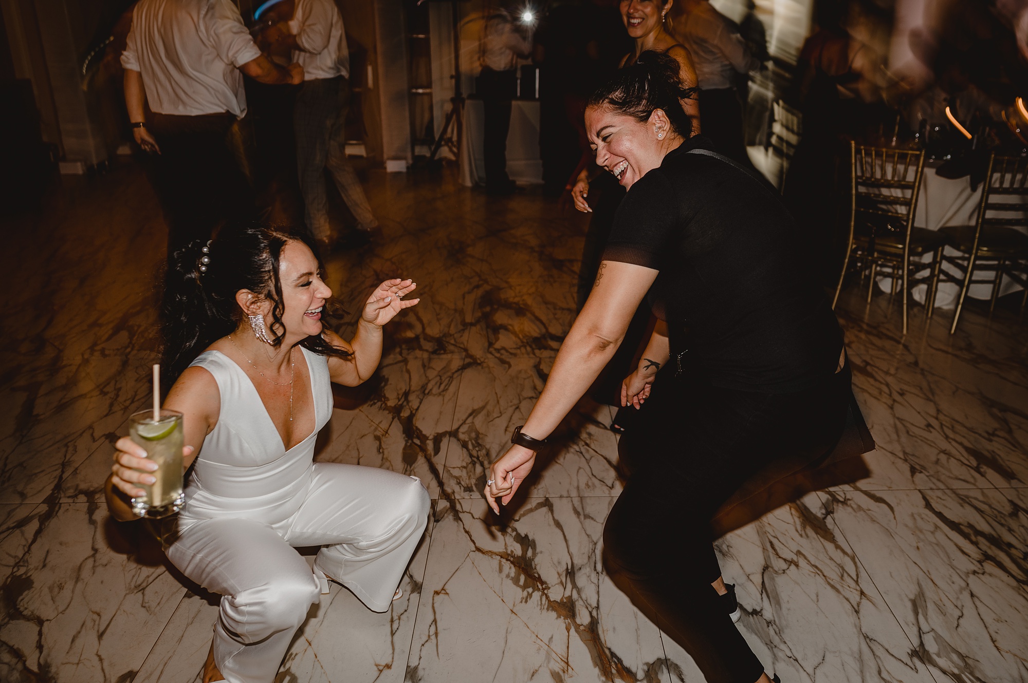 bride dances during reception in white jumpsuit