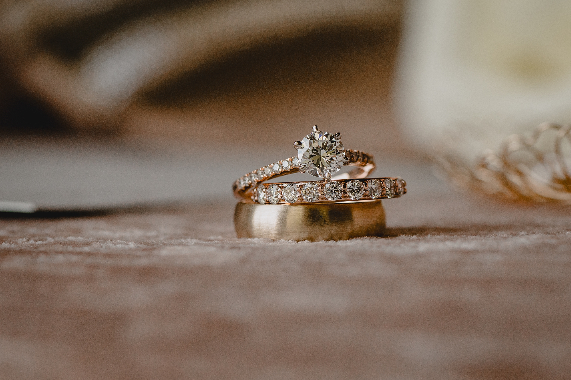 three wedding bands stacked together on pale pink floor