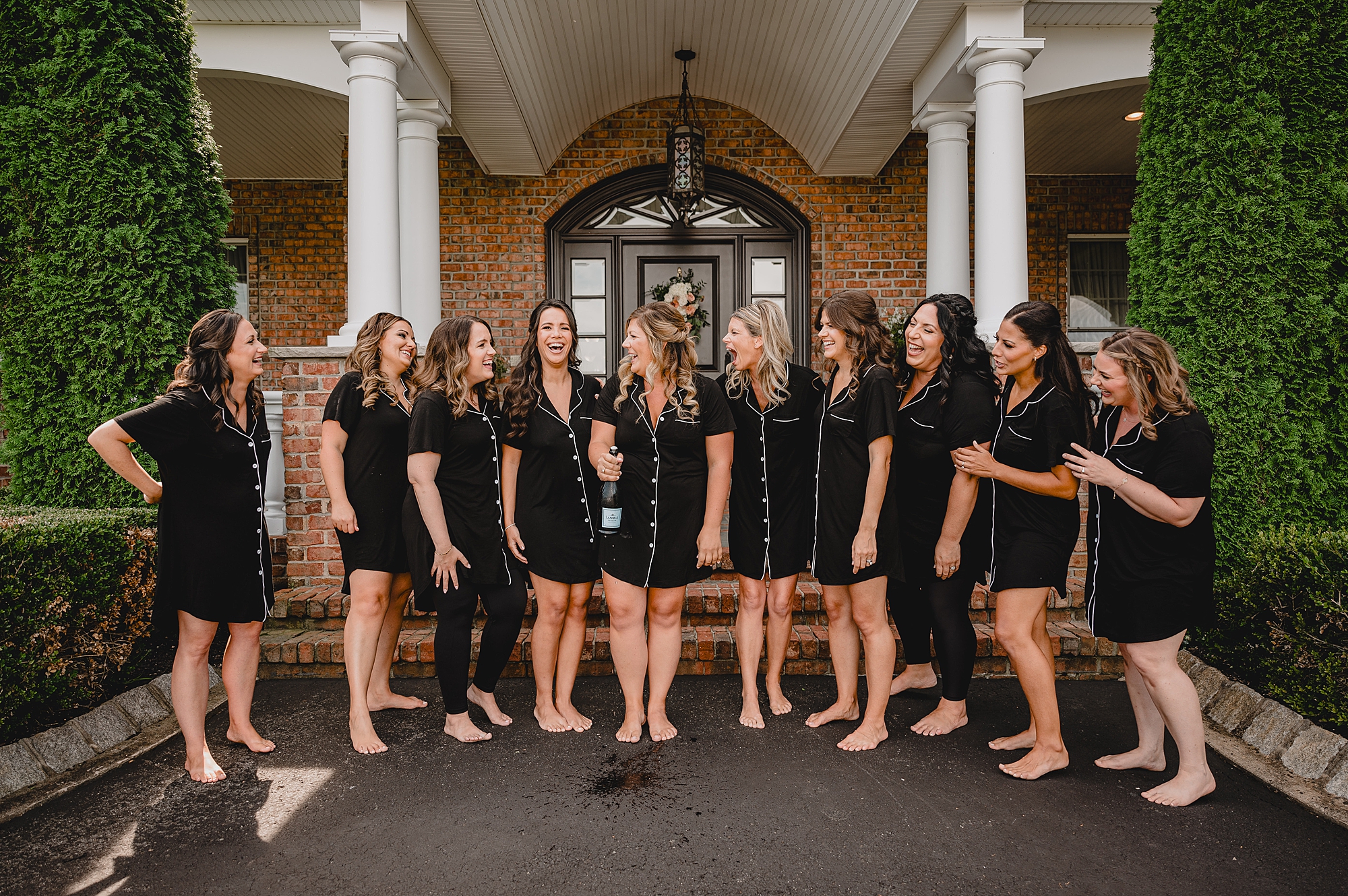 bride stands with bridesmaids in matching black and white pajamas in suite at the Mill Lakeside Manor