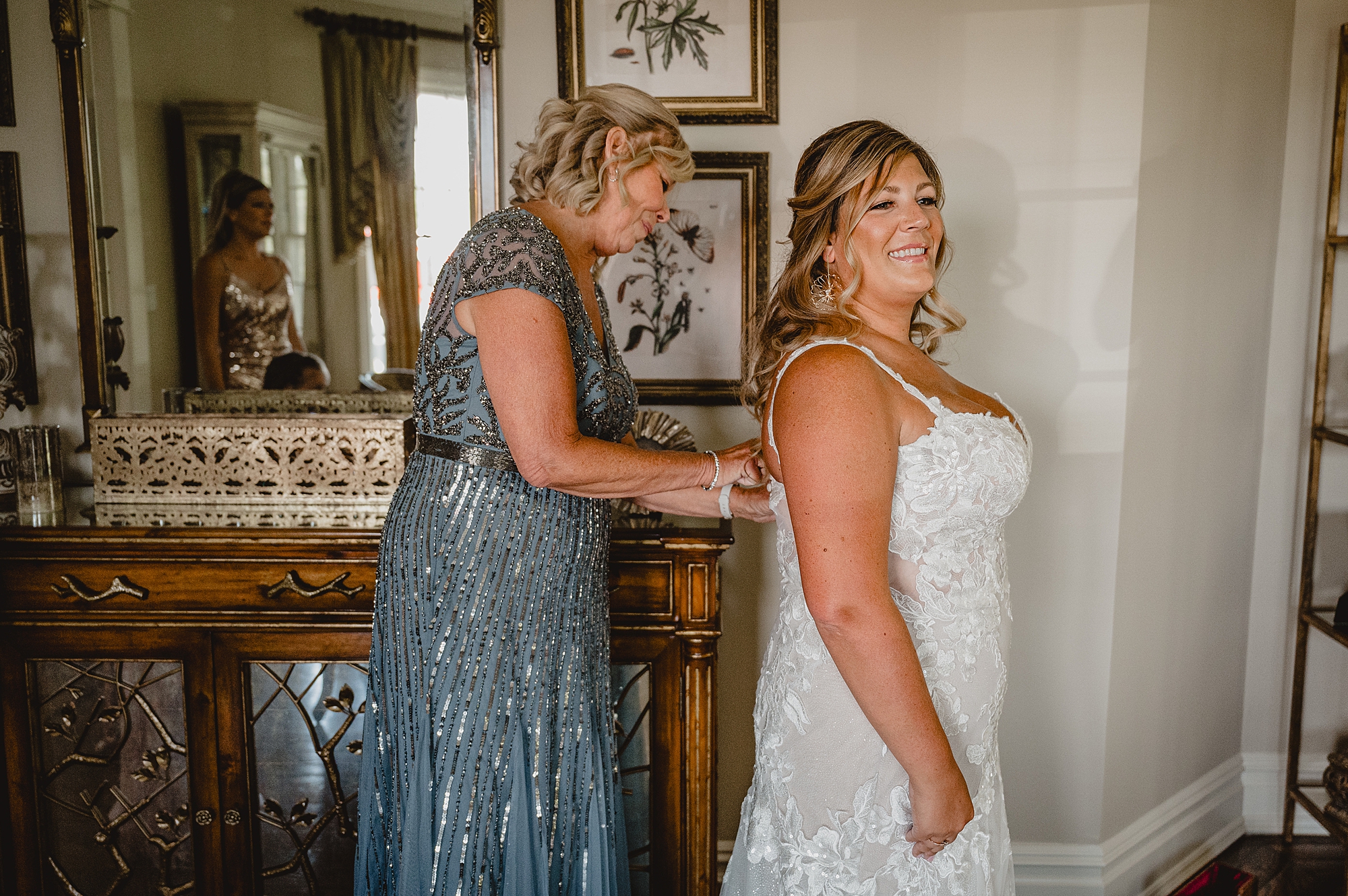 mother helps bride into wedding dress