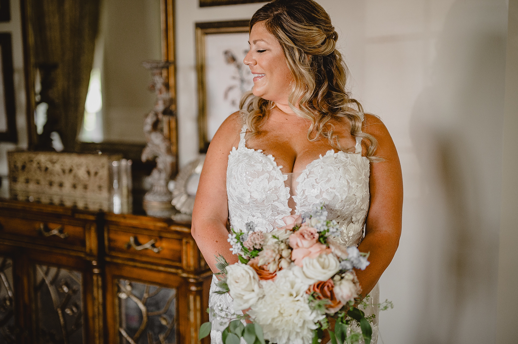 bride holds bouquet of white and pink flowers at the bottom of stairs
