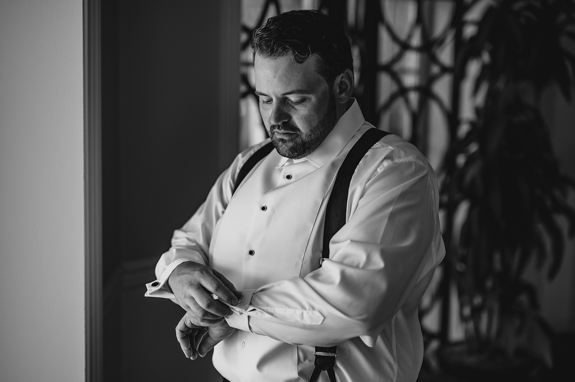 groom adjusts cufflinks during prep at the Mill Lakeside Manor