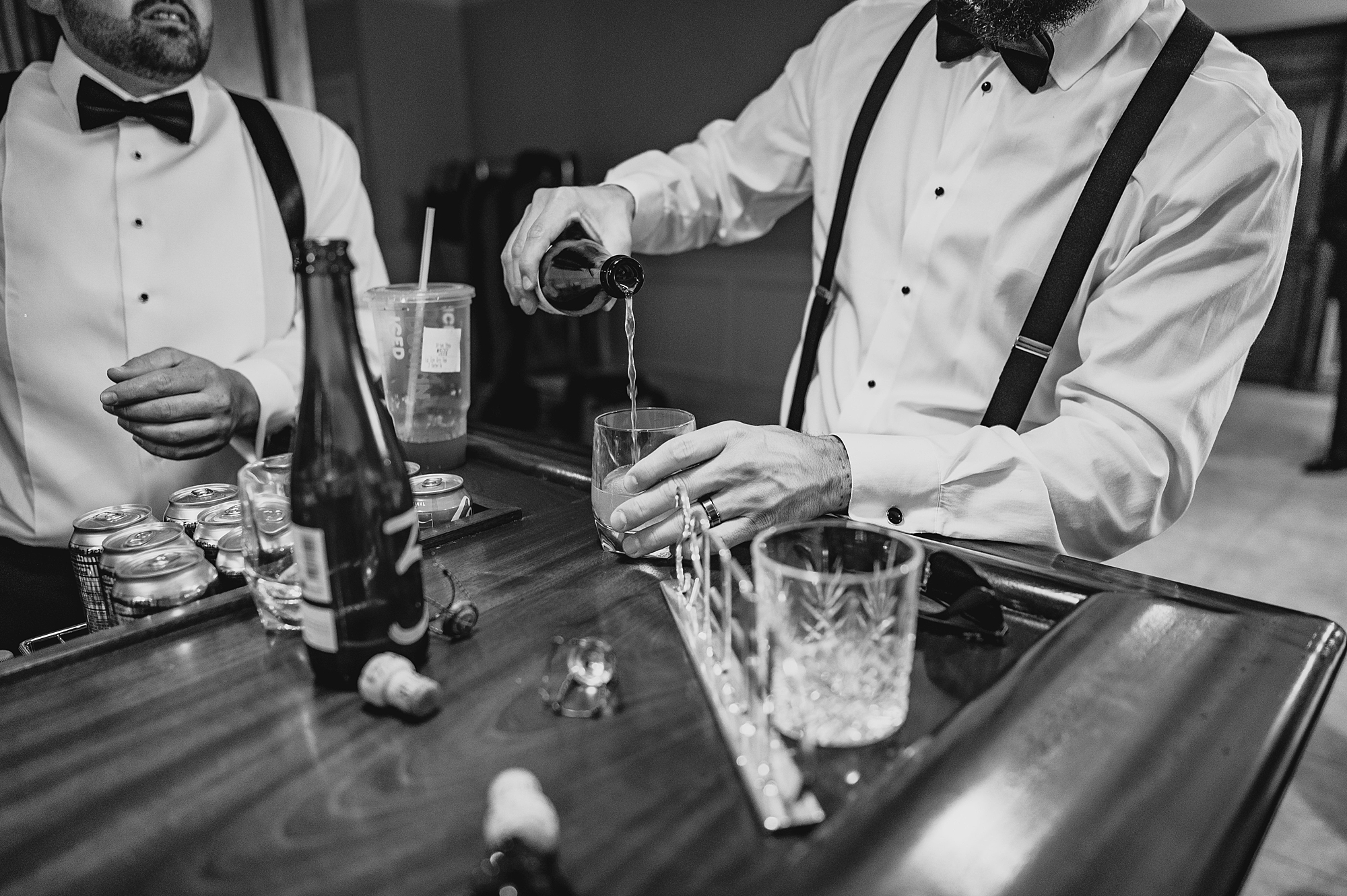 groom pours drinks during NJ wedding day for groomsmen