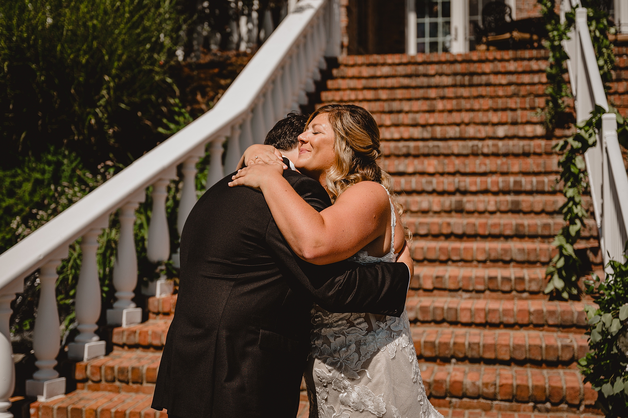 bride and groom hug by brick staircase outside the Mill Lakeside Manor