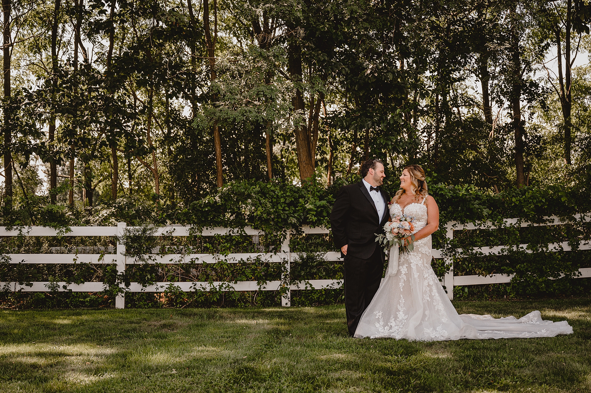 bride and groom stand by wooden fence at the Mill Lakeside Manor